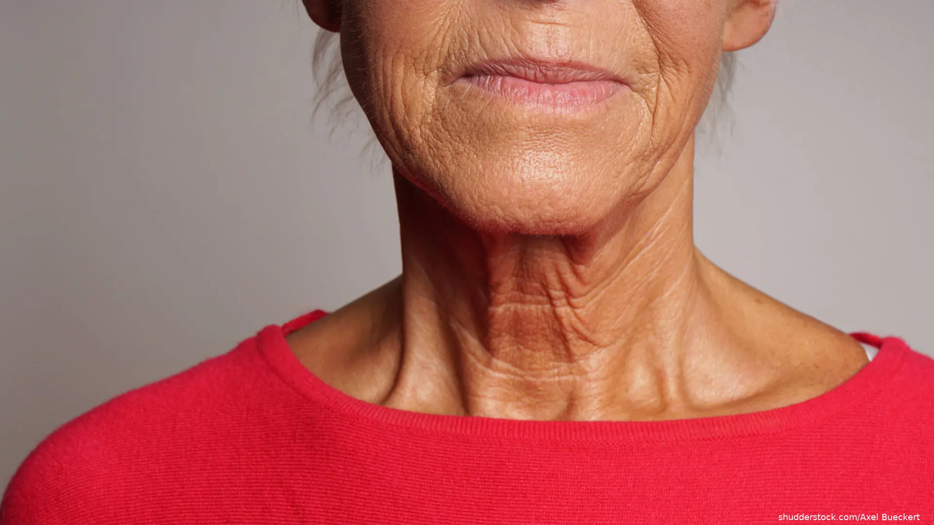 Detailed view of an older woman's neck and chin wearing a red shirt