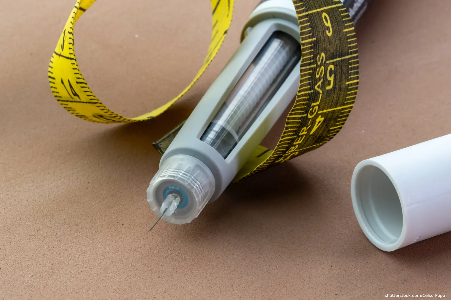 medical injection pen with a visible needle and a yellow measuring tape