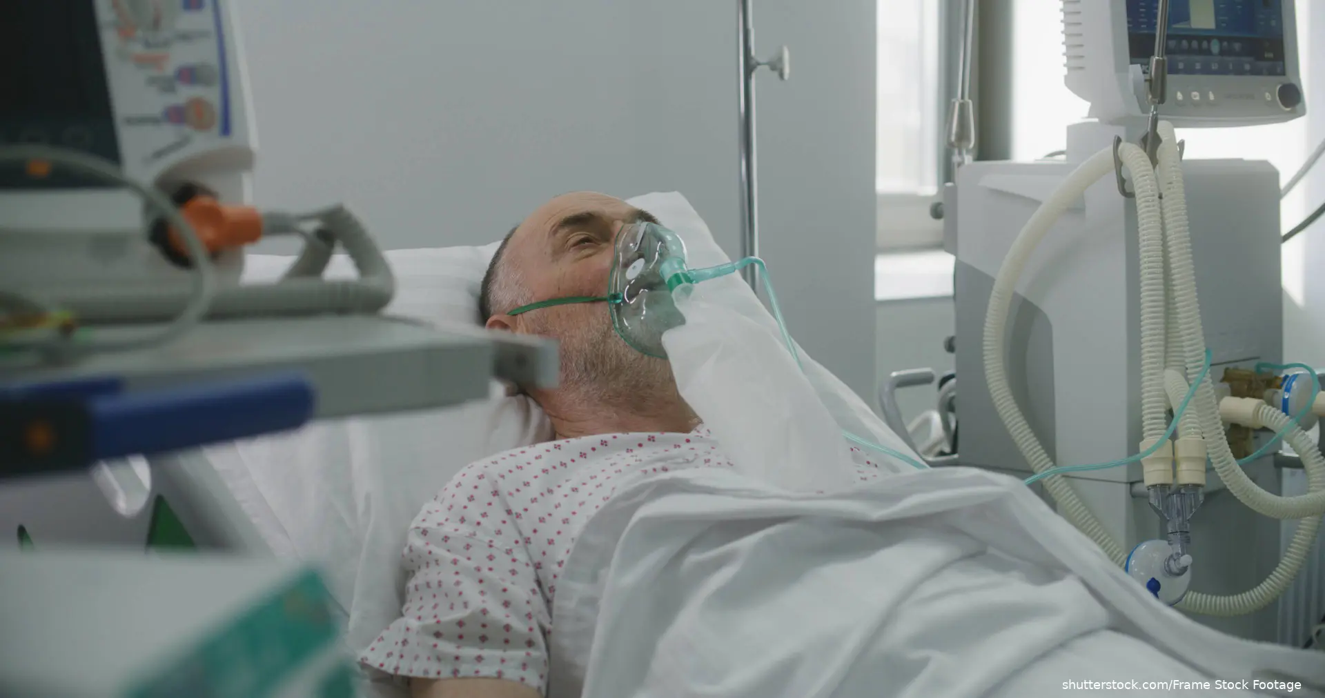 elderly man in hospital bed wearing oxygen mask