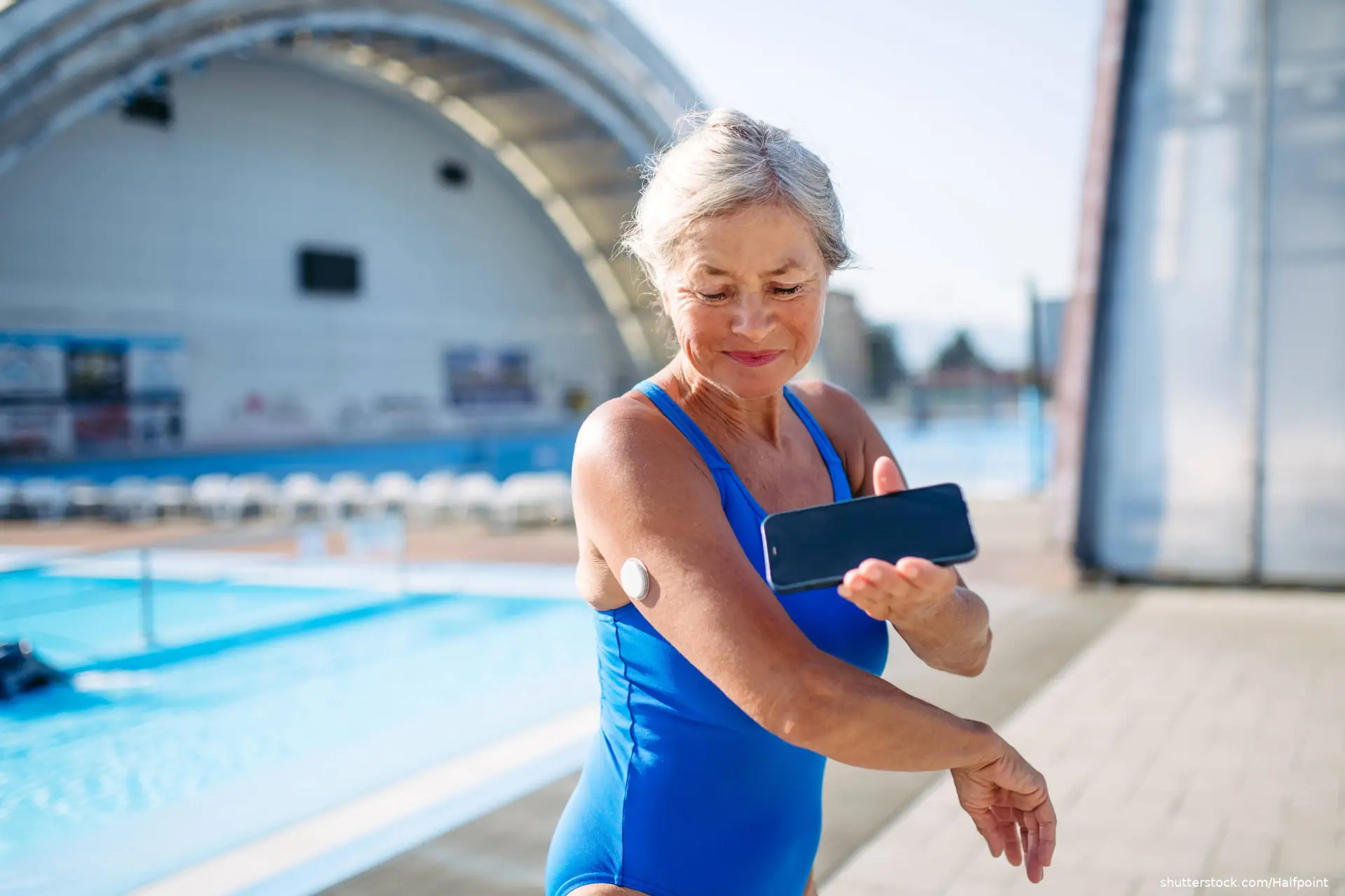 woman checking glucose on her phone before swimming.