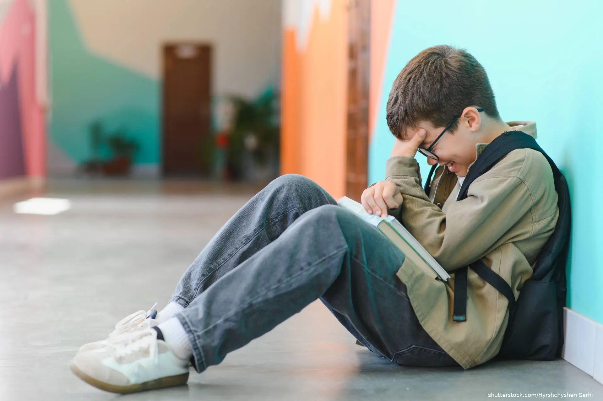 Schoolboy sitting on the floor, crying and feeling anxious