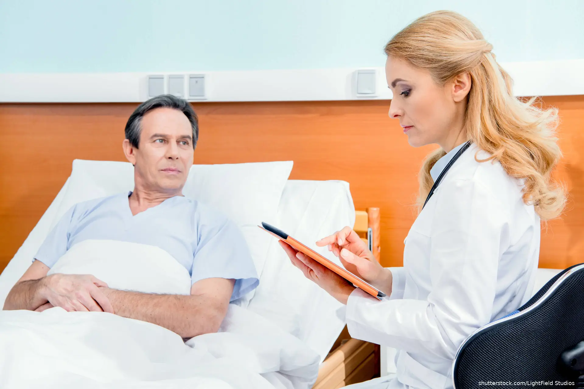 man in hospital bed talking to doctor