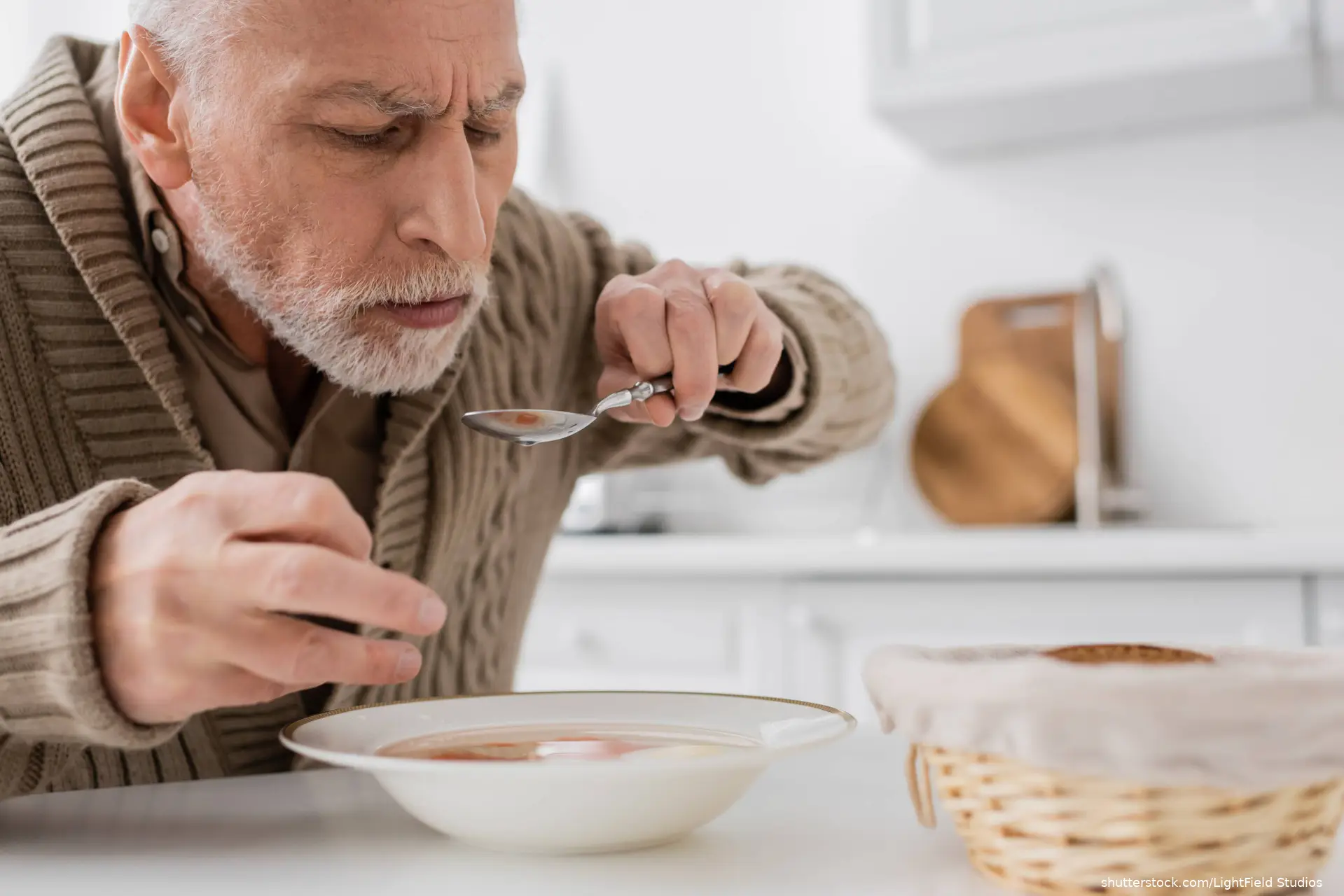 man with parkinson disease holding spoon in trembling hand while eating
