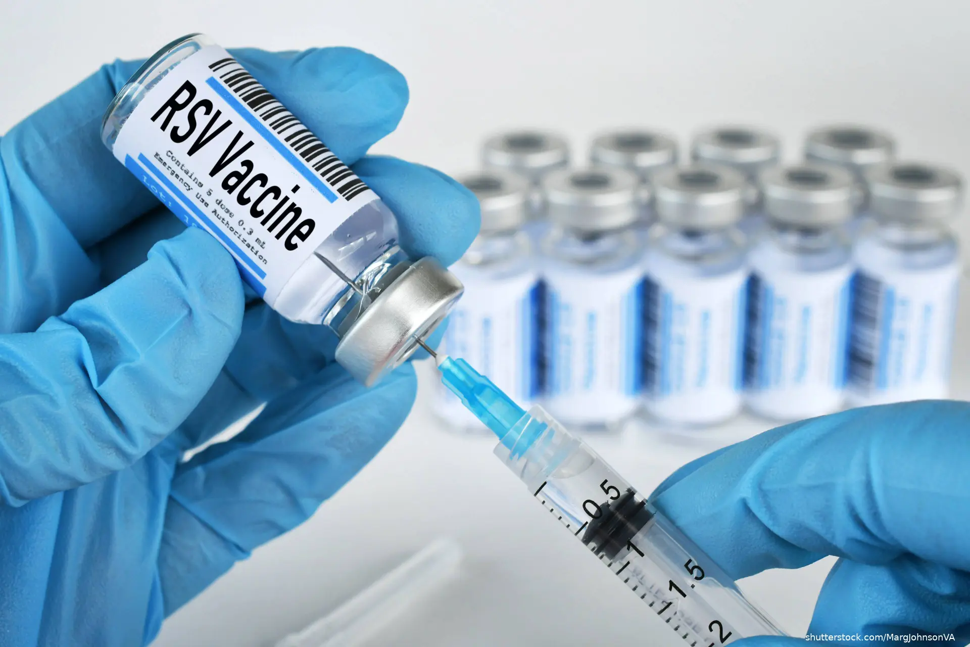 Medical personnel filling a syringe needle with RSV vaccine from vial