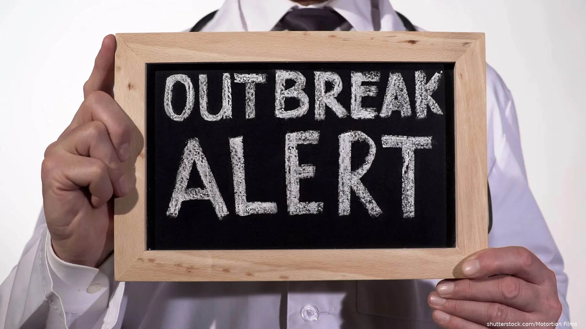 chalkboard being held by doctor the reads Outbreak Alert