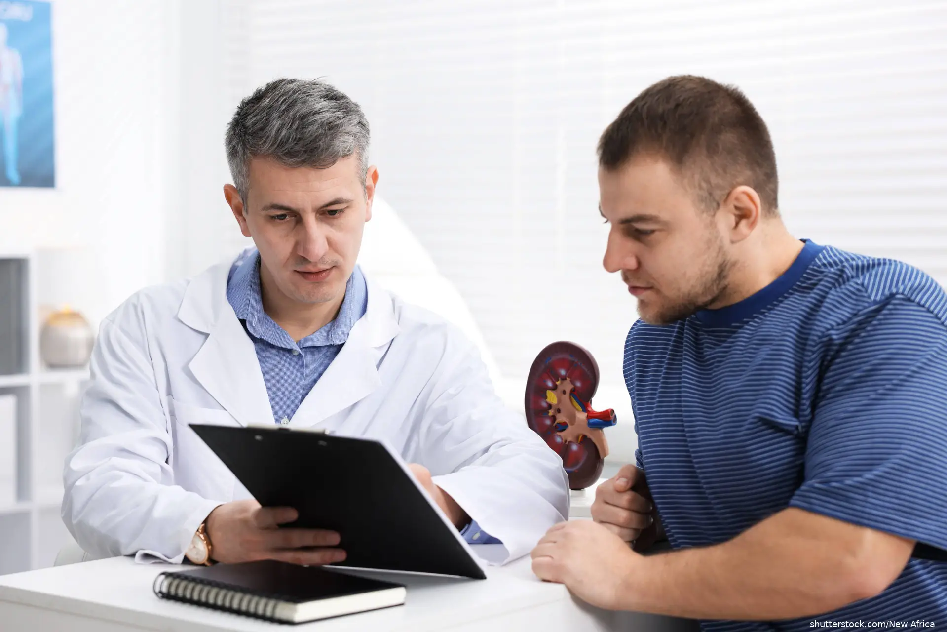 Urologist showing clipboard to patient at white desk in clinic