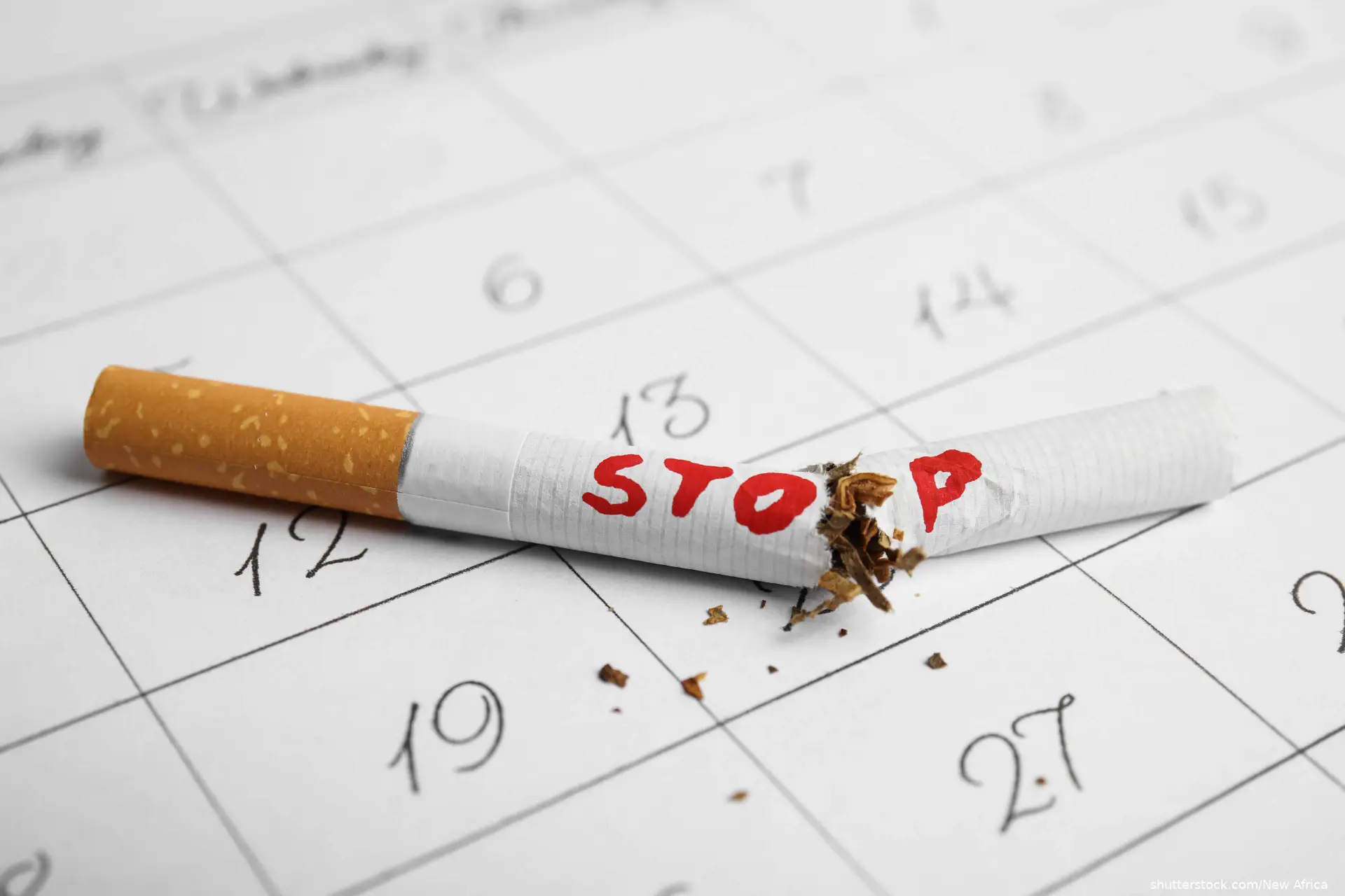 Broken cigarette with word Stop on calendar sheet