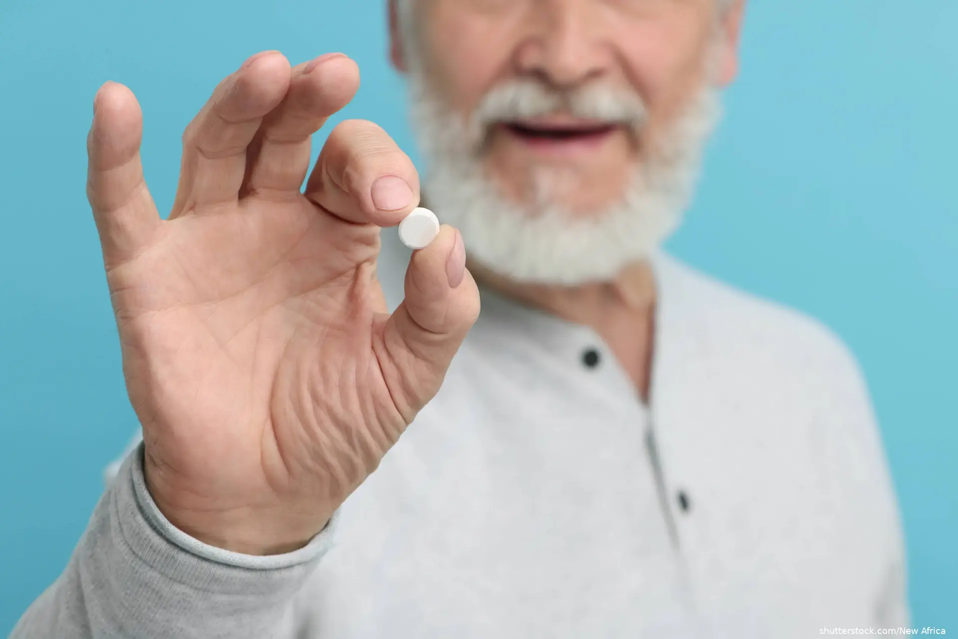 Senior man with pill on light blue background