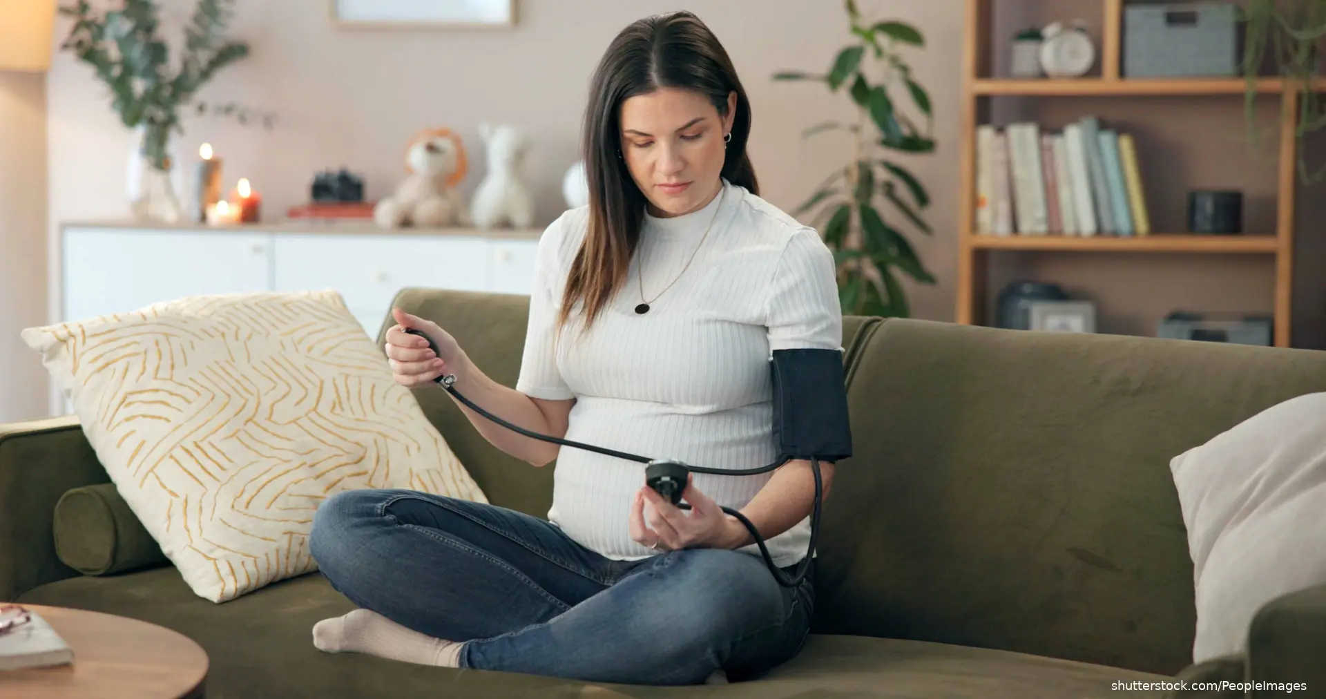 pregnant woman sitting on couch taking blood pressure