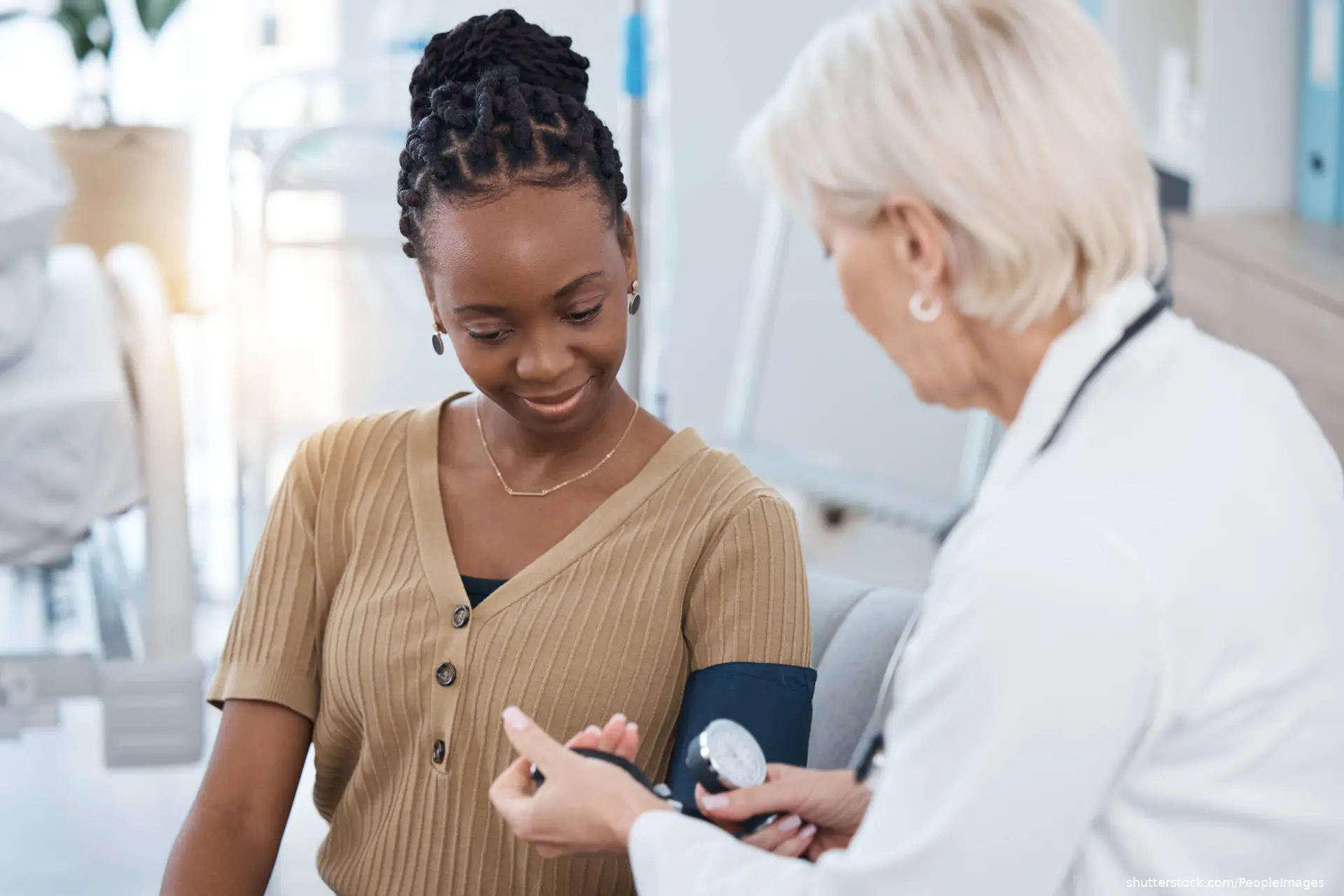 doctor taking blood pressure of young adult woman