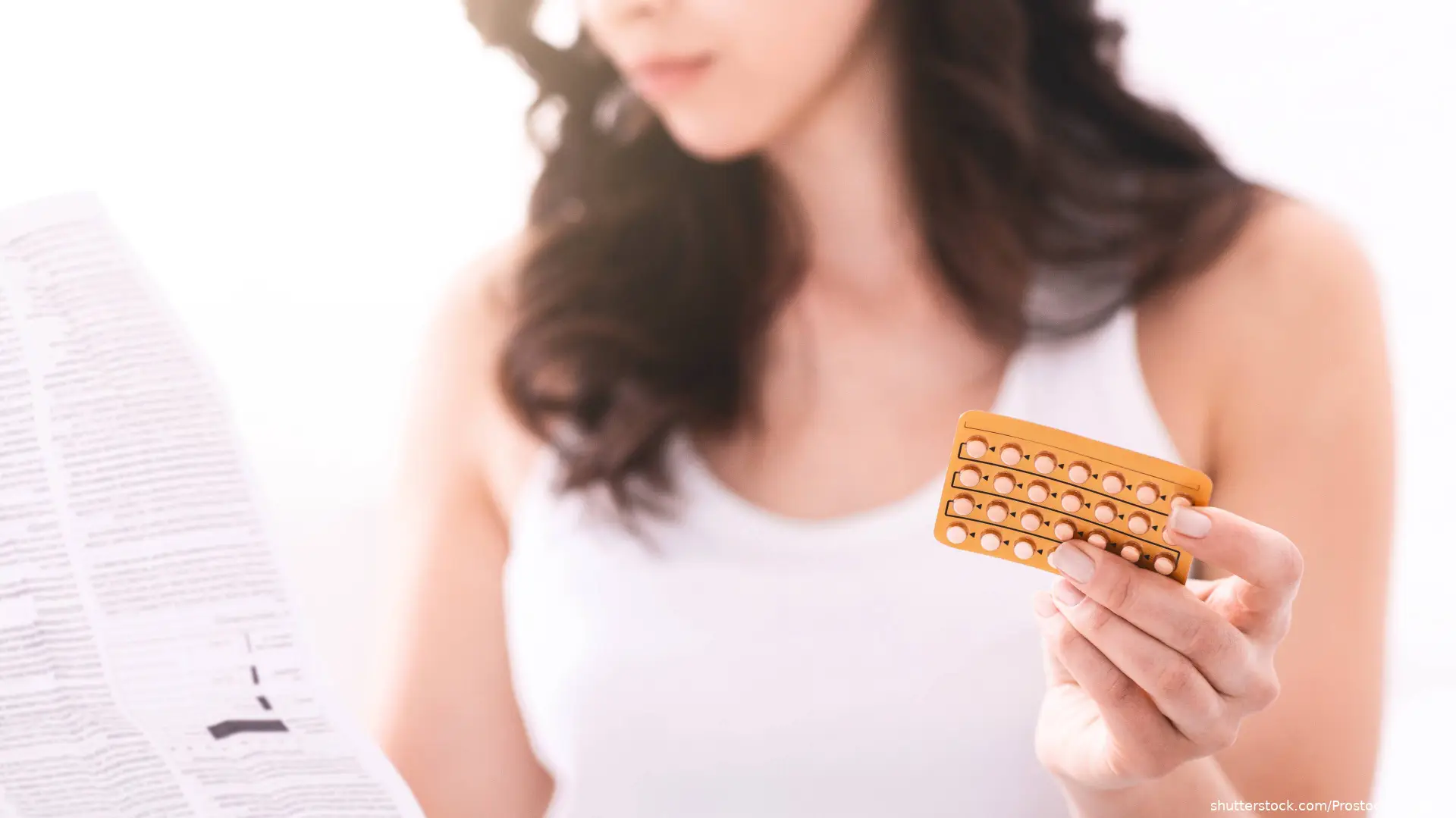 A woman is holding a pack of birth control pills