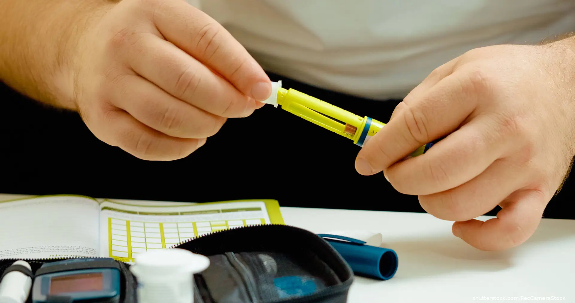 hands holding insulin pen dose schedule and supplies on table