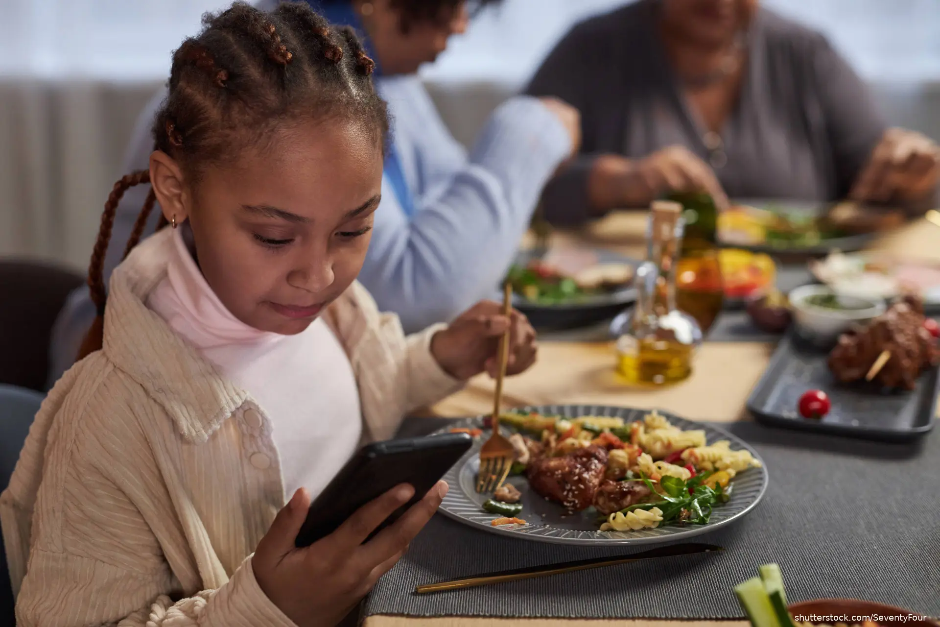 little girl using smartphone at dinner table