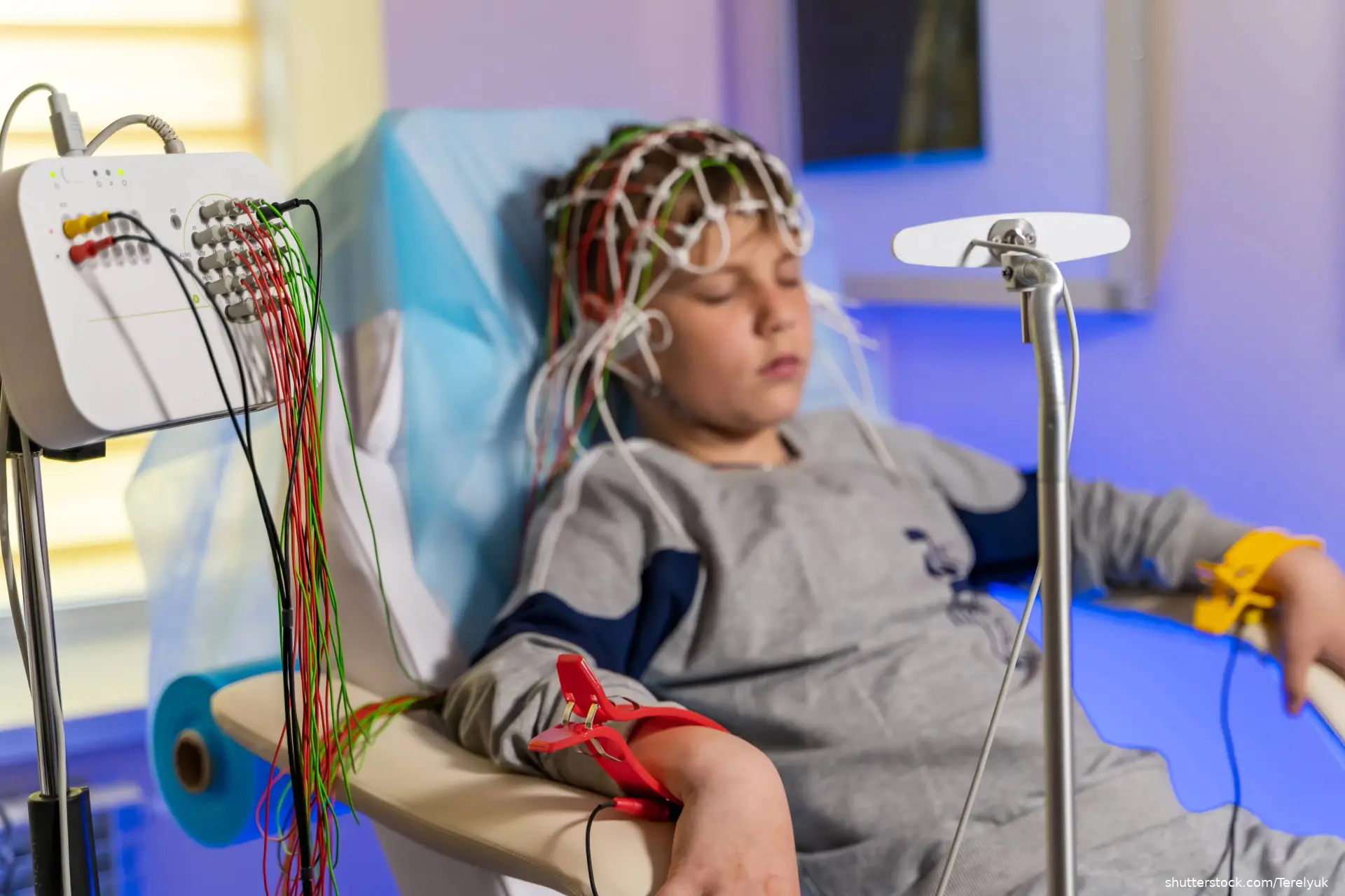 Boy sitting in chair wearing electrodes during electroencephalograph