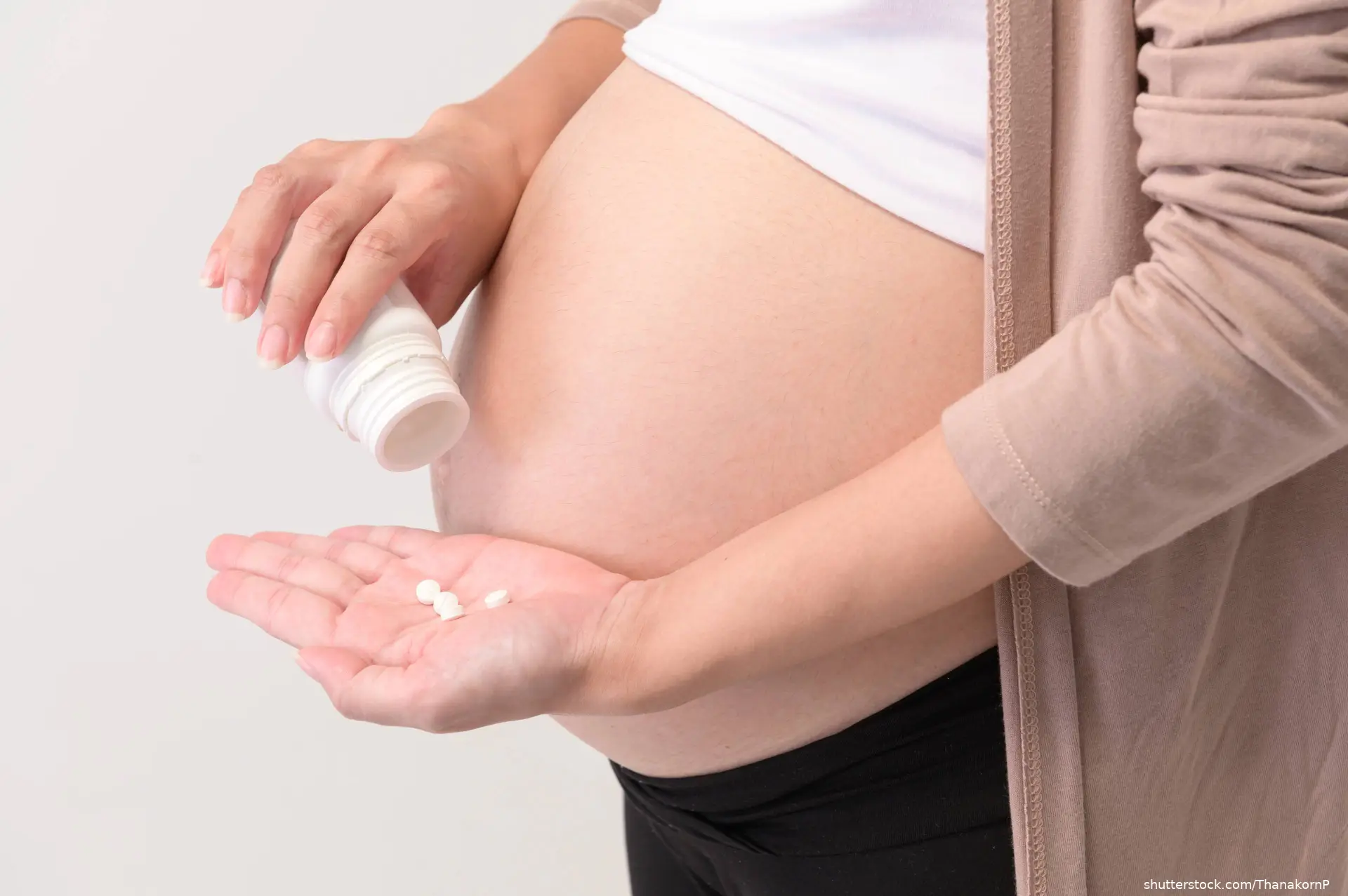 pregnant woman holding pills and pill bottle