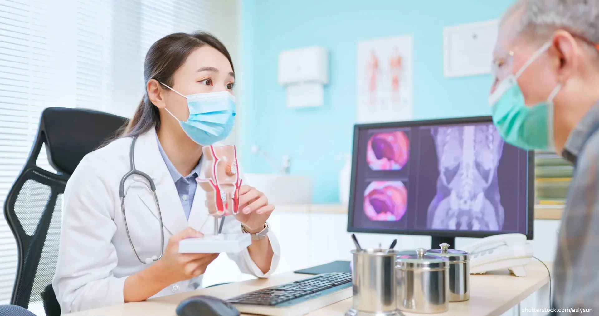 doctor wearing face mask is showing a rectal model