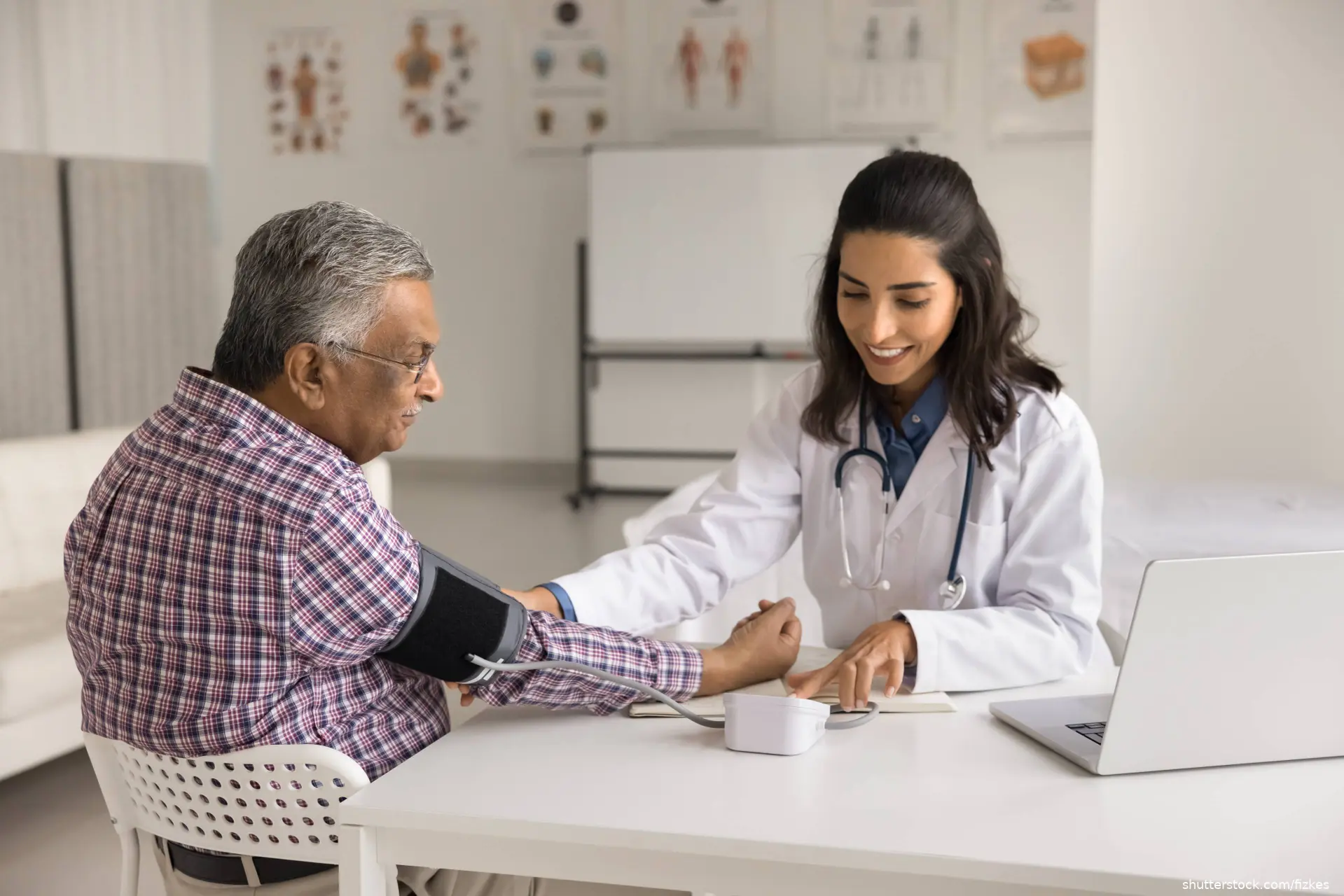 hispanic man getting blood presure taken by young female doctor