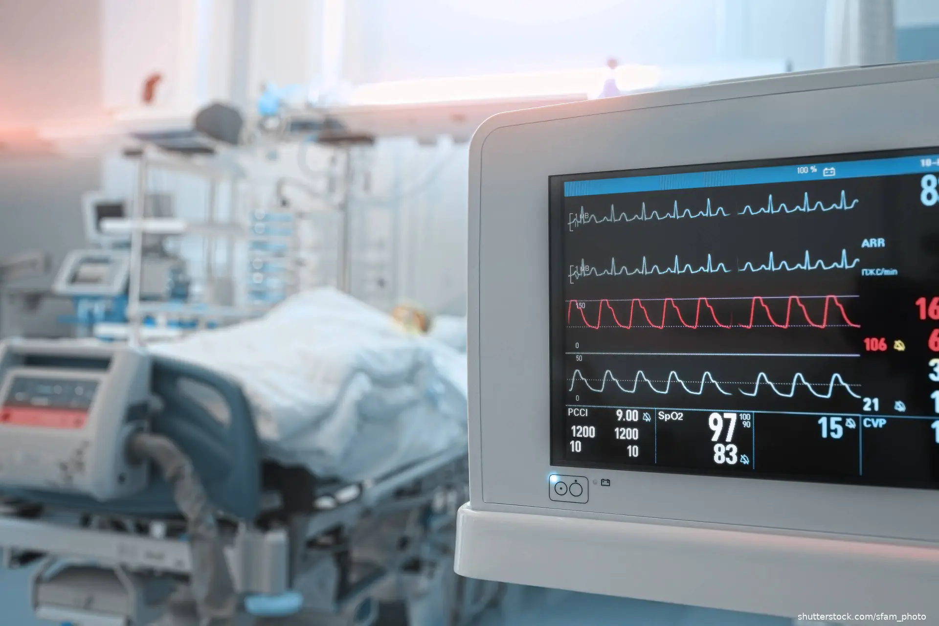 patient in hospital bed and heart monitor in foreground