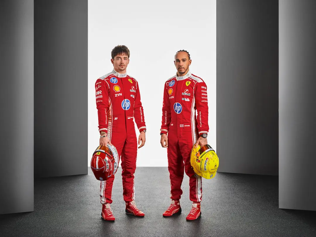I due piloti della Scuderia Ferrari per il 2026, Charles Leclerc e Lewis Hamilton in piedi con uno sfondo bianco e grigio