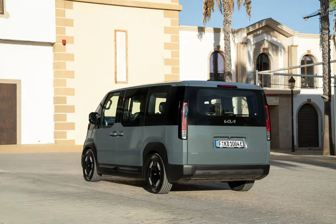 La vista di tre quarti posteriori della Kia PV5 Passenger con verniciatura grigia e nera