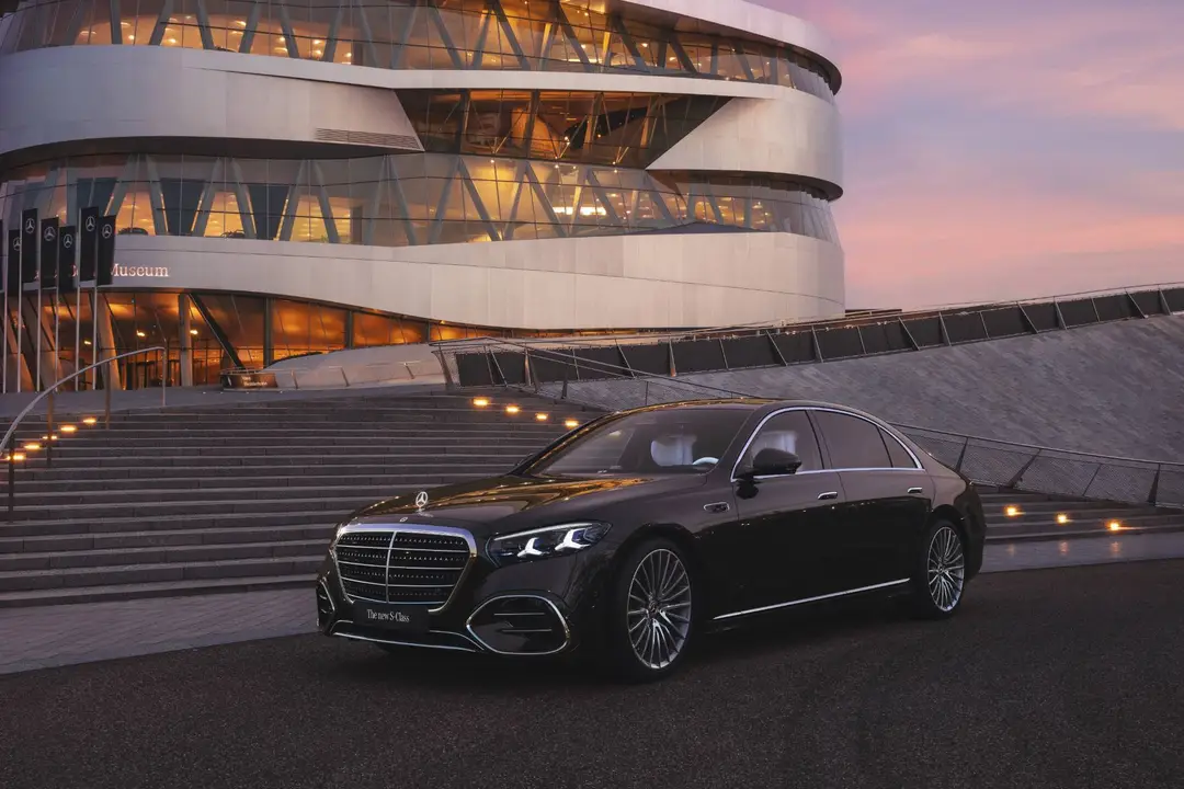 Vista frontale laterale della mercedes benz classe s 2026 scura con lo sfondo con sfondo del museo mercedes
