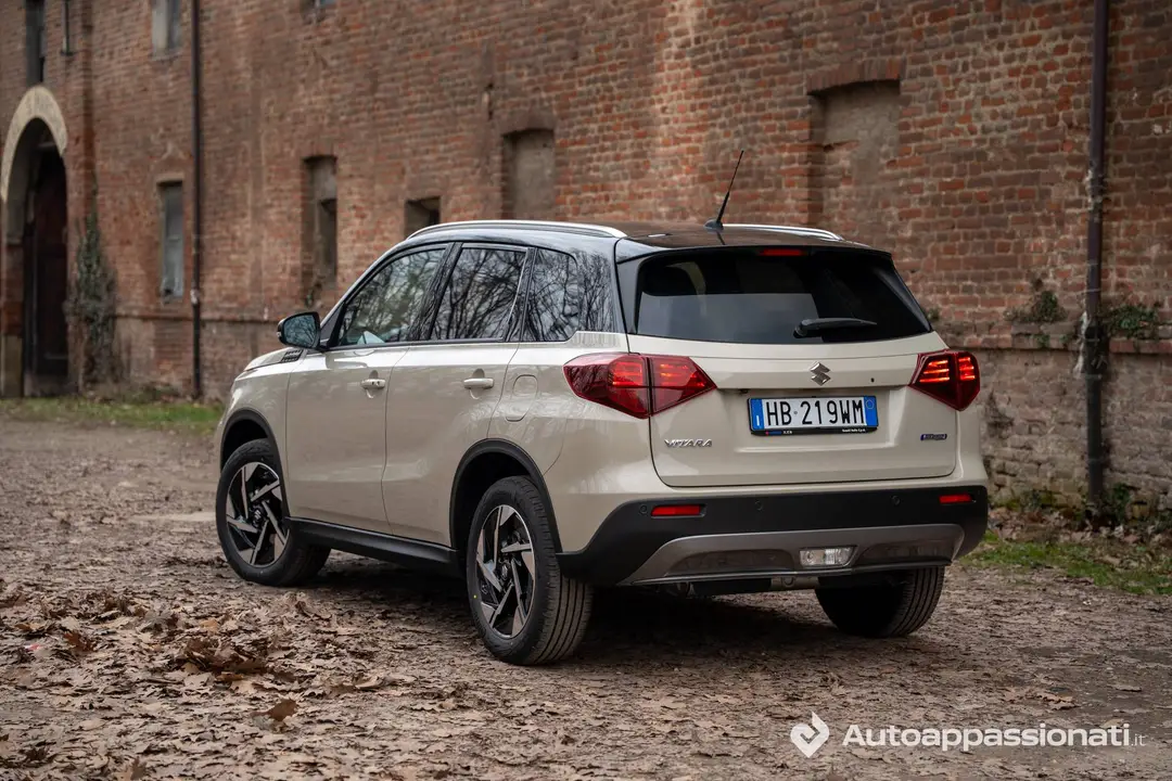 Foto del posteriore tre quarti della Suzuki Vitara Hybrid AllGrip 2026, in colore sabbia e fotografata in un ambiente contadino