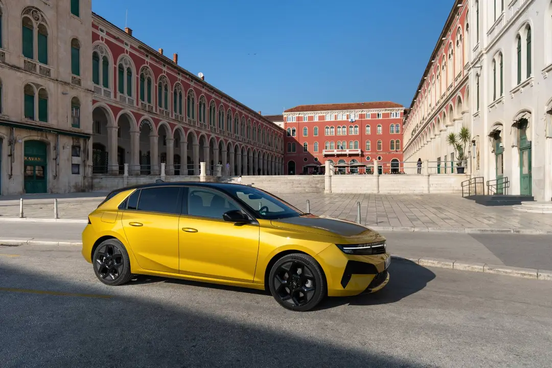 Opel Astra di colore giallo in posizione laterale in una piazza