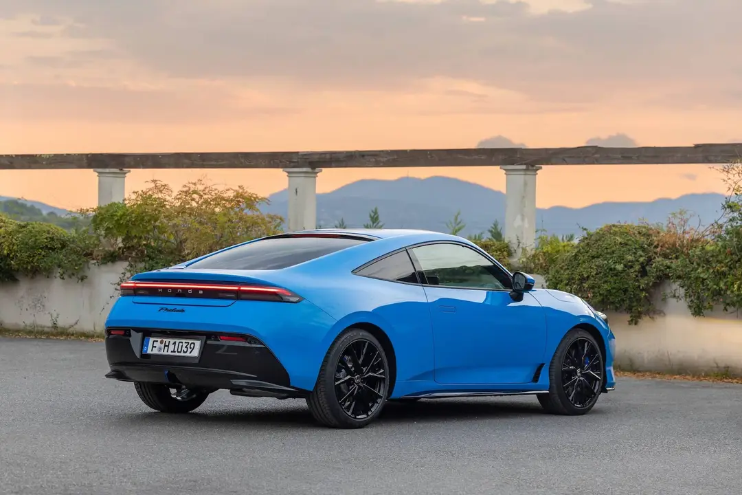 La nuova Honda Prelude Hybrid 2026 verniciata in blu fotografata di tre quarti posteriore con un tramonto e un ponte alle sue spalle