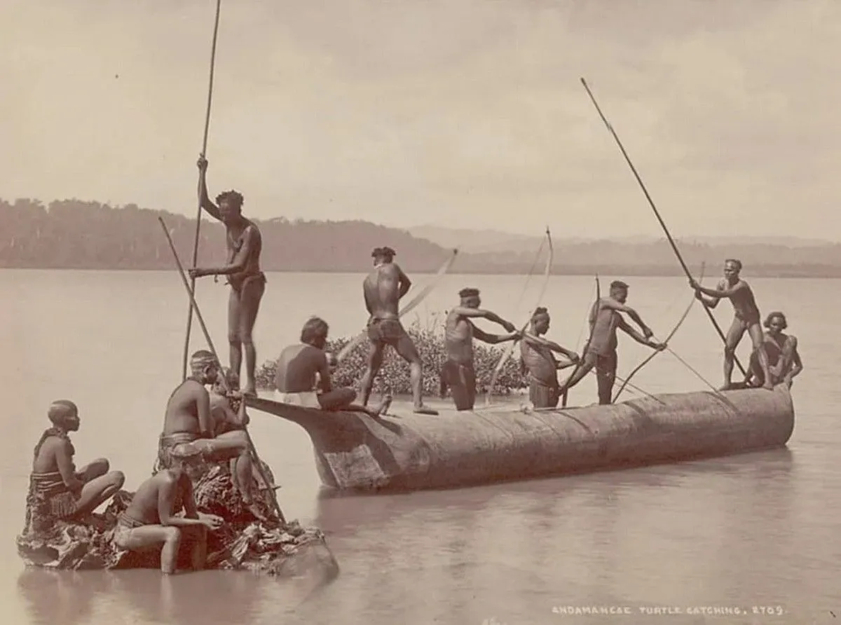group of andaman men and women in costume some wearing body paint and with bows and arrows catching turtles from boat on water