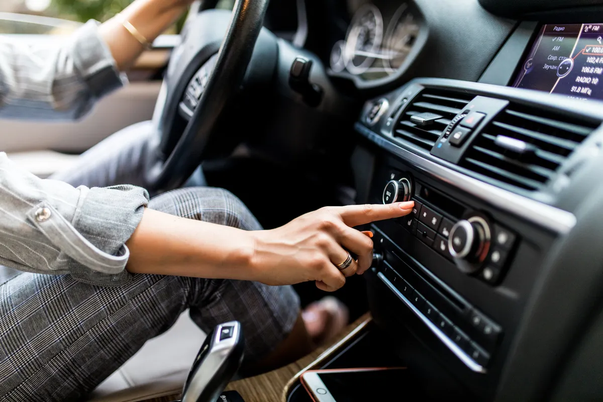 car dashboard radio closeup woman sets up radio while driving car