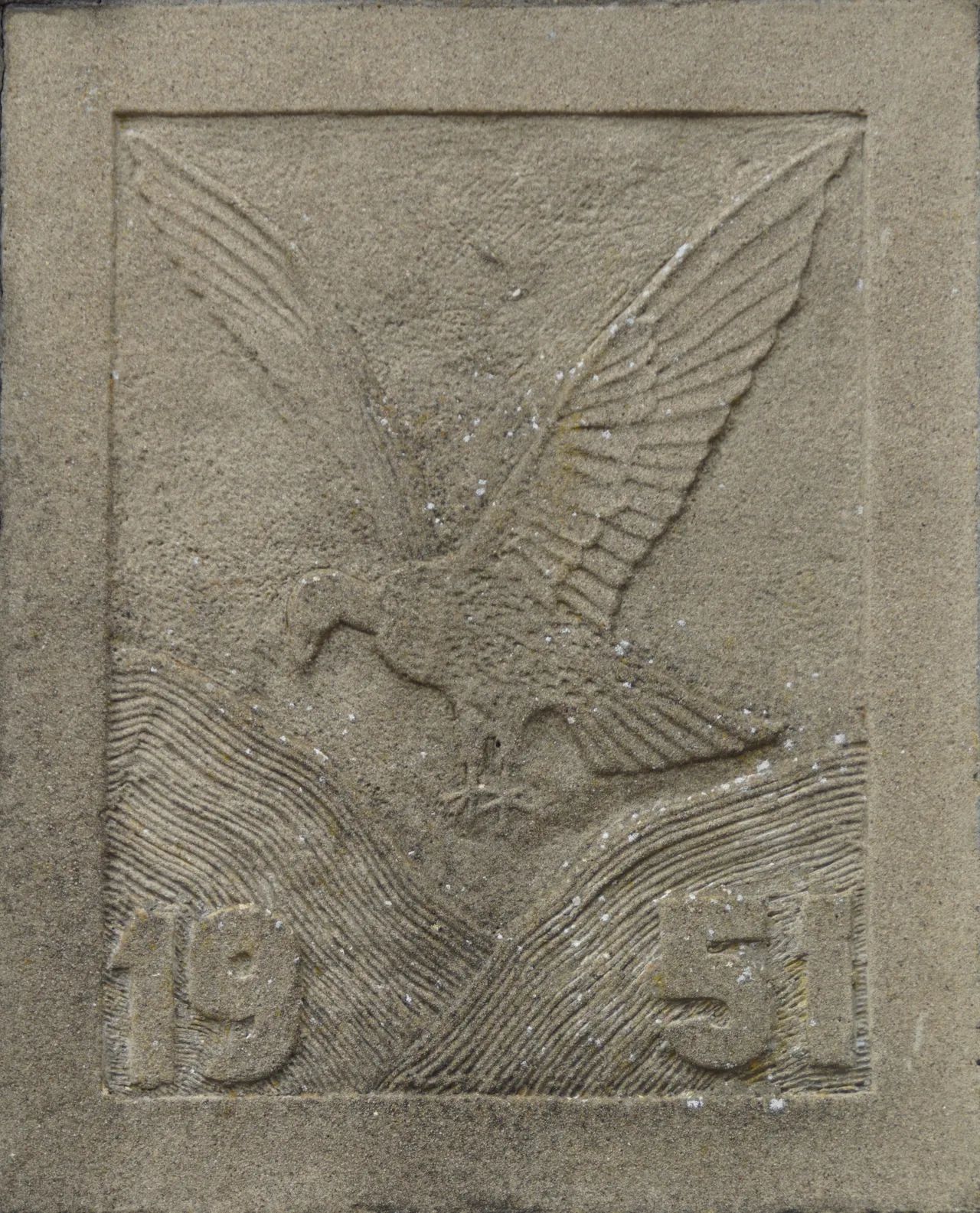 De voorzijde van de pomp is versierd met een plaquette, voorstellende een GIER, zwevende boven de BERGEN (duinen) met het jaartal 1951. Met gieren wordt hier bedoeld het heen en weer bewegen van de stuifzandheuvels.