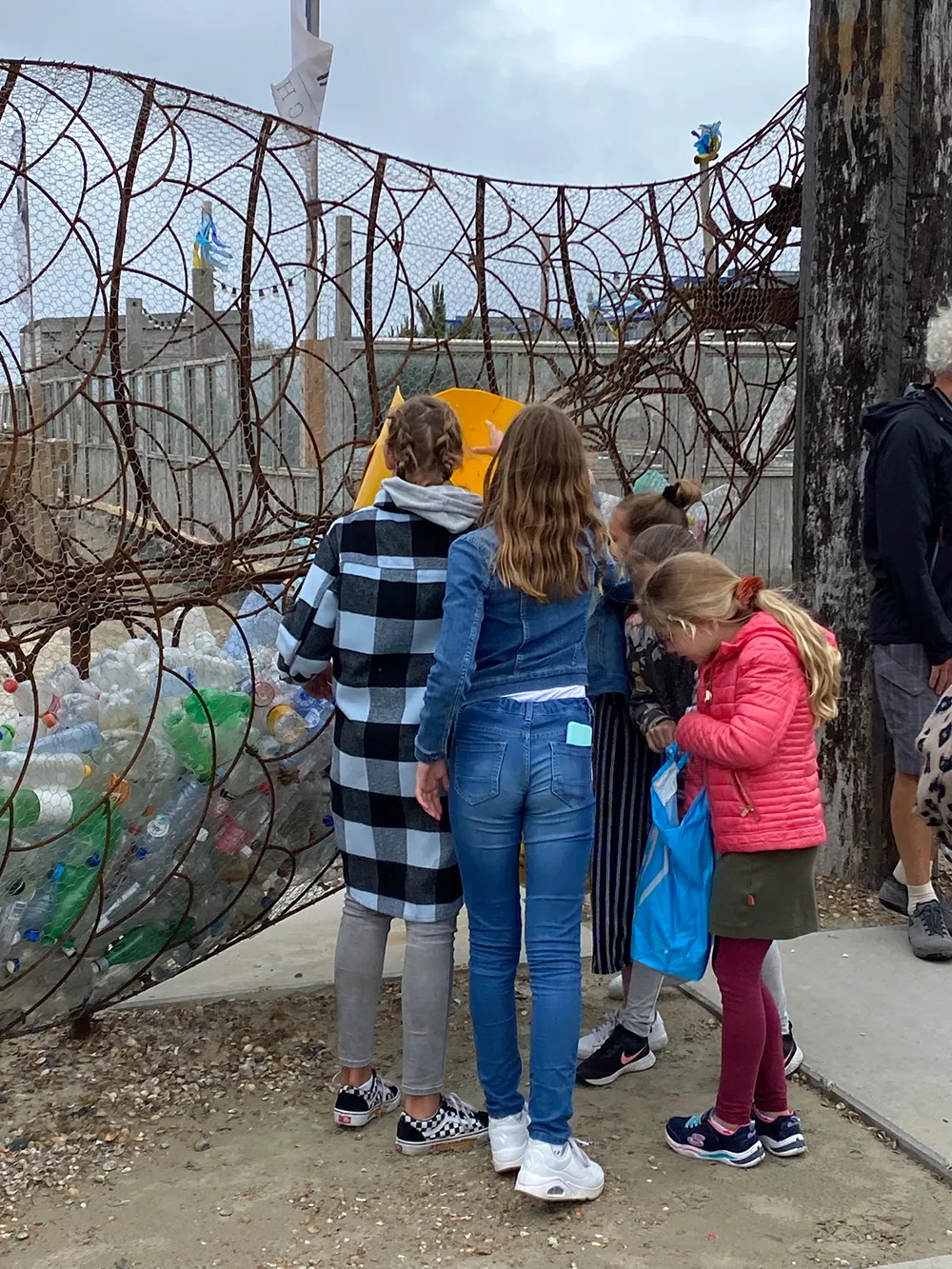 leerlingen van het kompam uit ijmuiden gooien plastic flessen in kunstwerk catchfish