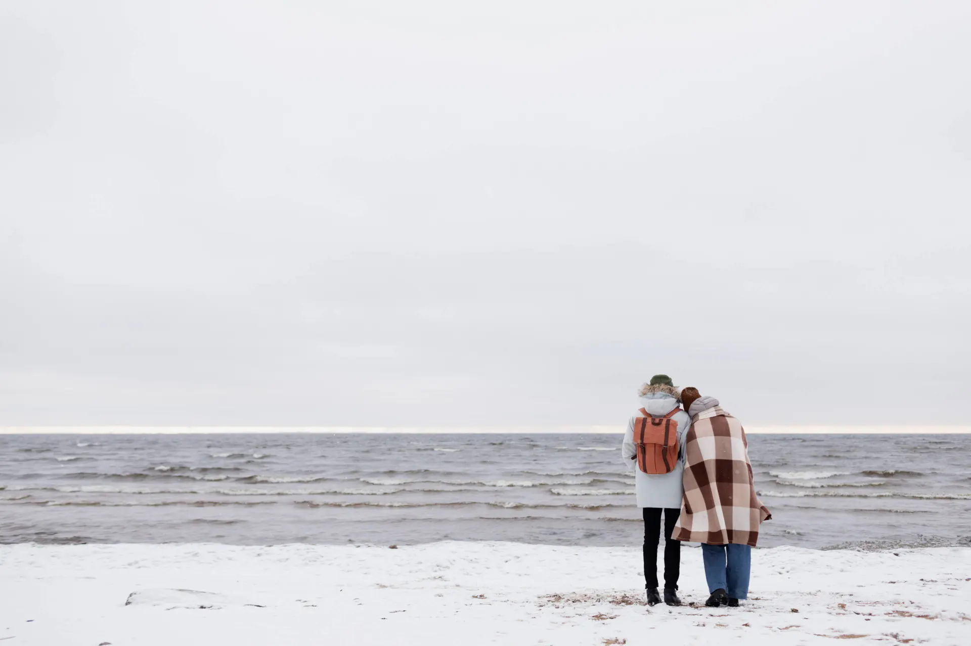 couple-waking-by-beach-together-while-winter-road-trip