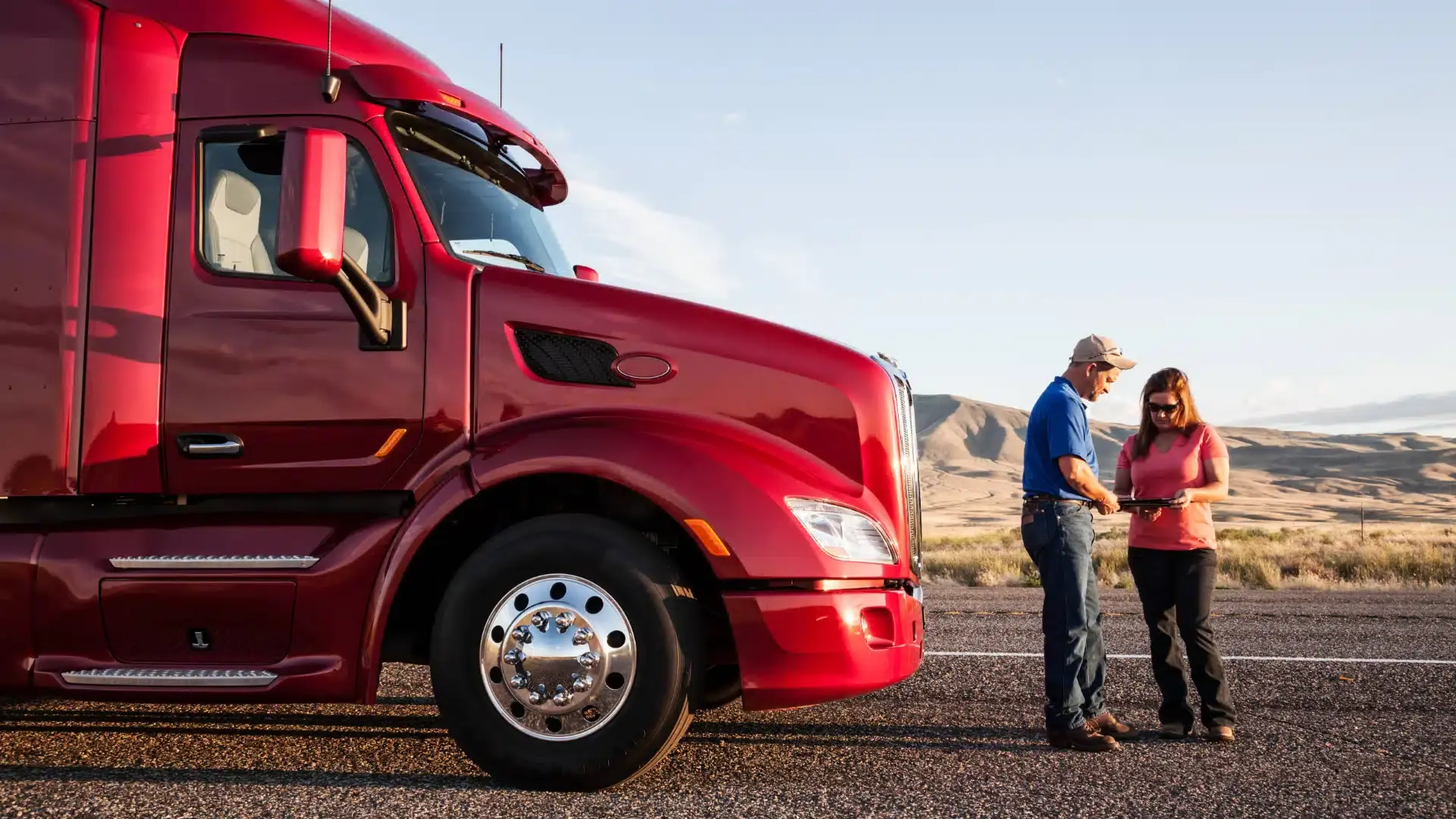 Nell'immagine si vede un camion americano di colore rosso con davanti due persone che parlano.