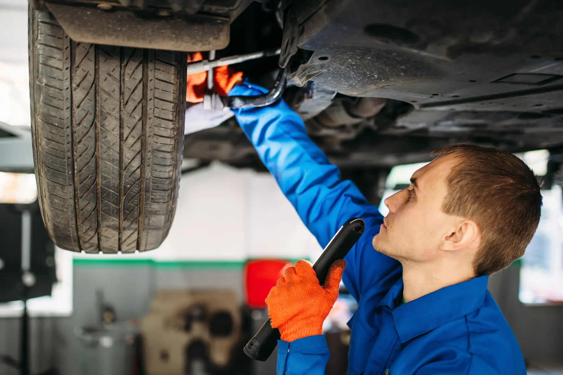mechanic with lamp checks the car suspension 2021 08 26 16 26 18 utc