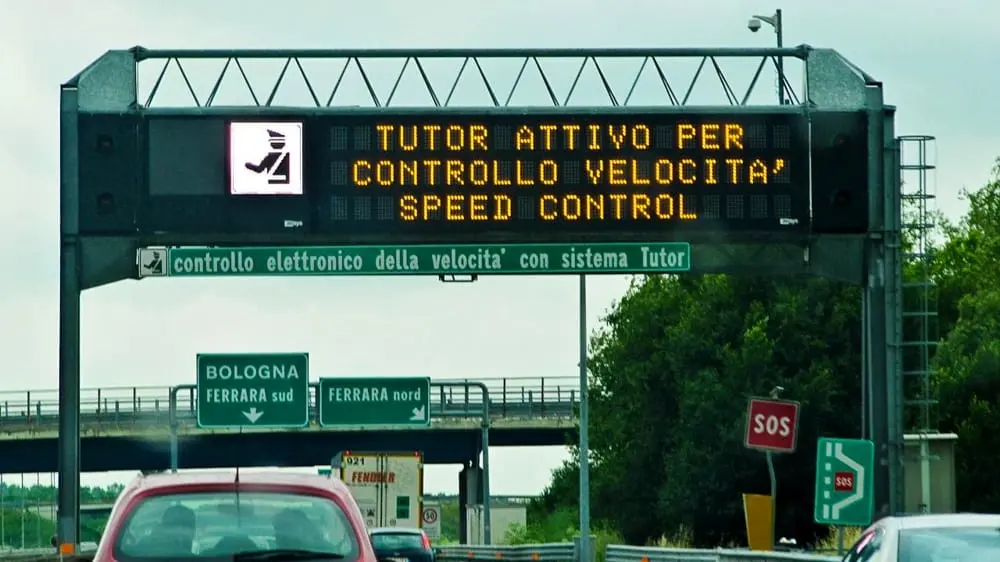 sistema tutor sull'autostrada italiana, si vede un cartello luminoso e una scritta che avvisano della presenza del tutor