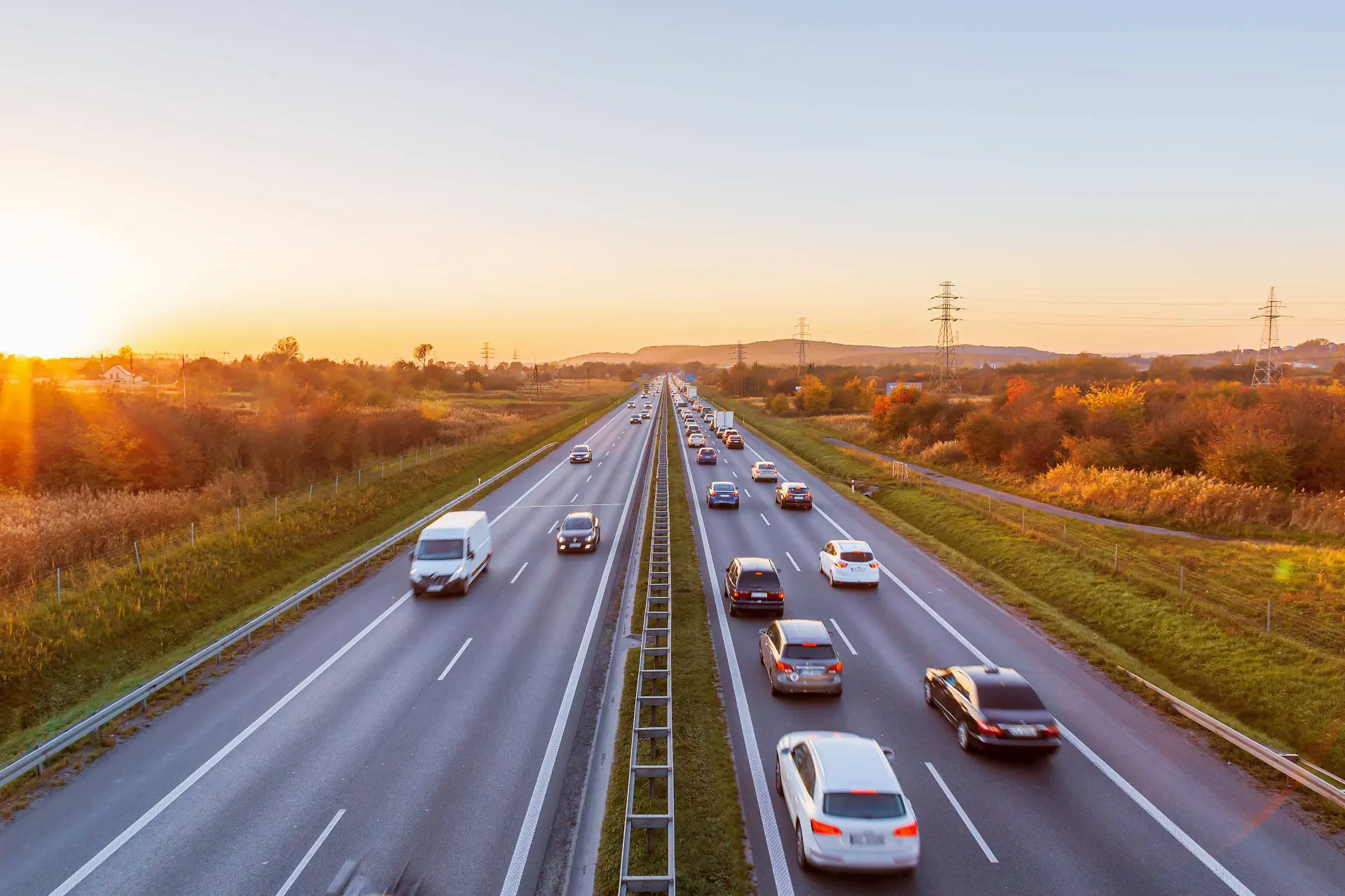 Autostrada al tramonto con diverse auto che la percorrono in entrambi i sensi