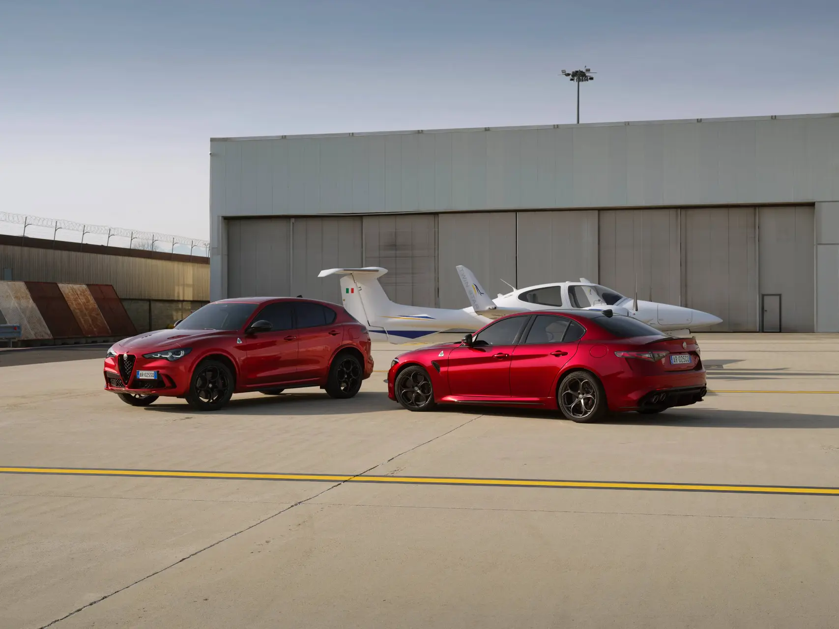 Le Alfa Romeo Giulia e Stelvio Quadrifoglio riprese in un aeroporto con dietro un aereo cessna
