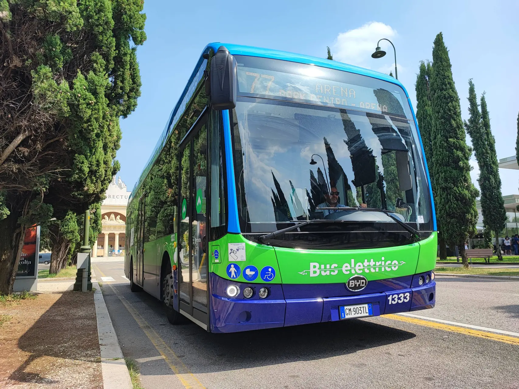 BUS di colore verde e blu della marca BYD in collaborazione con ATV di Verona su una strada tra due file di alberi