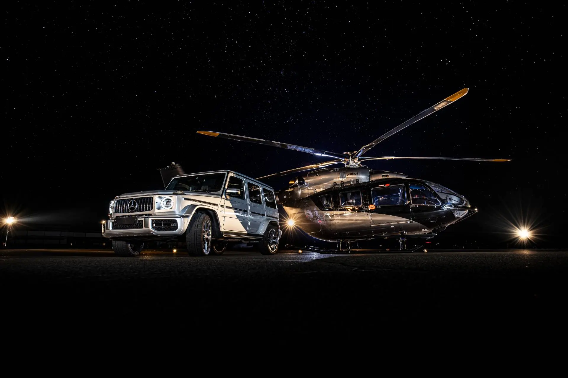 Elicottero di Airbus con Mercedes Benz Classe G al suo fianco di colore grigio