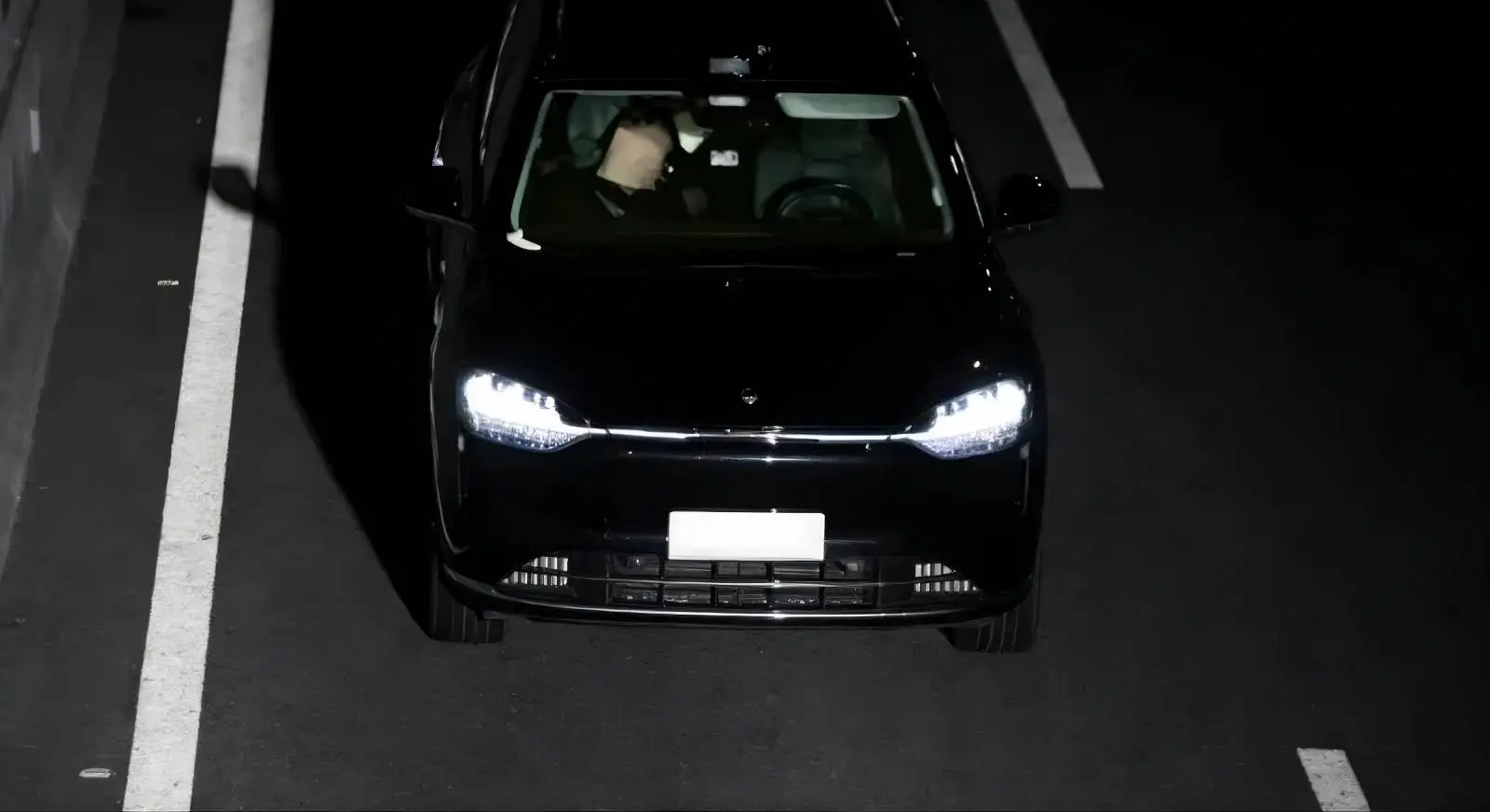 foto fatta da una telecamera che mostra un'auto  nera con il sedile conducente vuoto e sul sedile passeggero un uomo che dorme