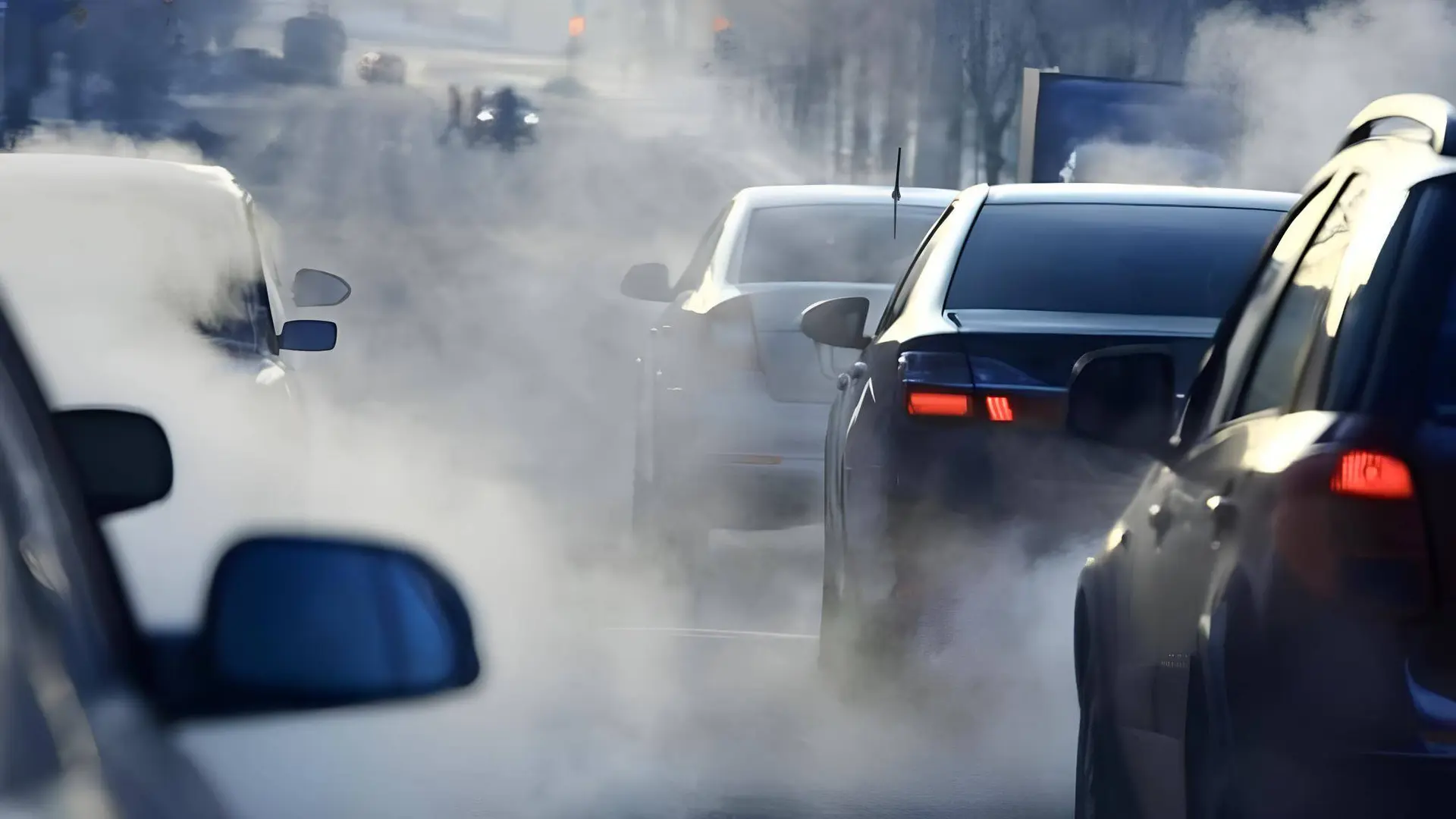 nell'immagine si vedono delle auto ferme in coda e una cortina di fumo generata dai gas di scarico delle macchine
