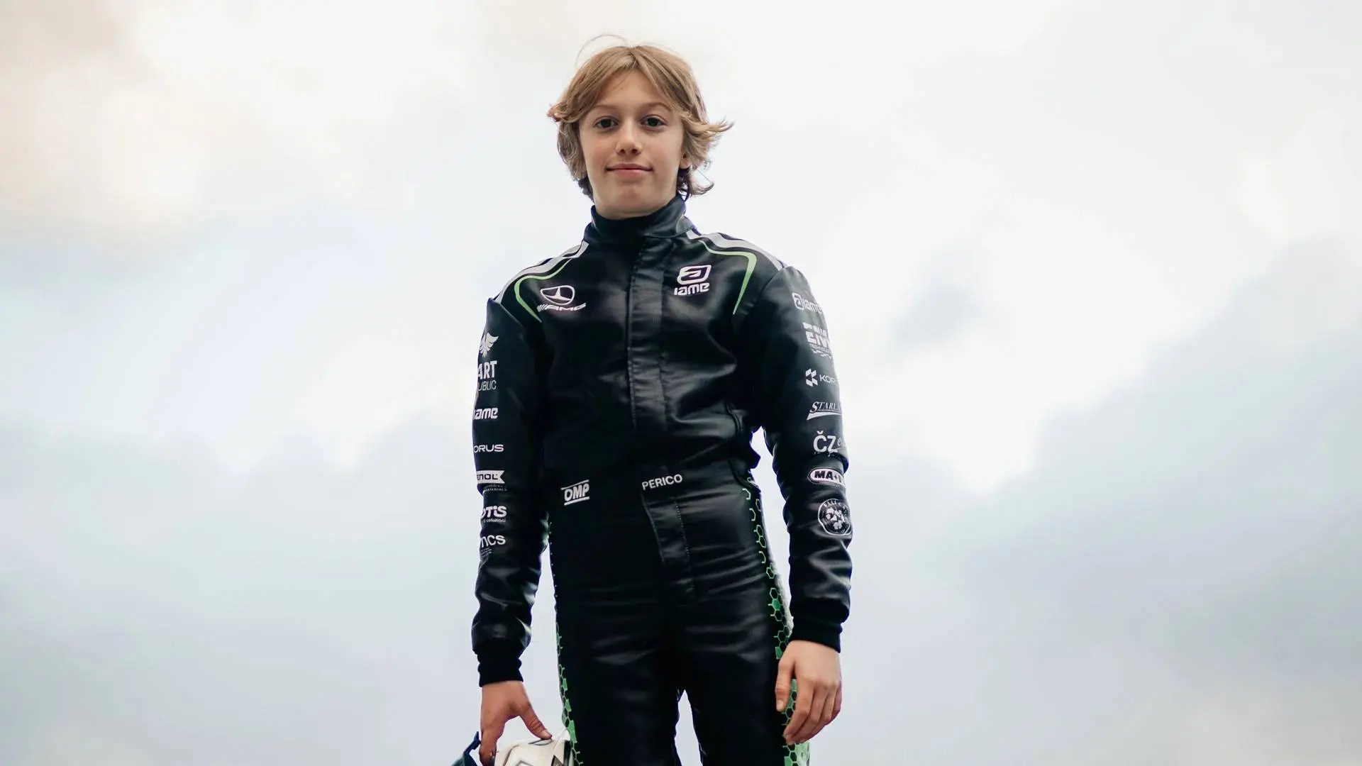 Niccolo-Perico pilota Mercedes Junior Program in piedi con la tuta mercedes e il casco in mano