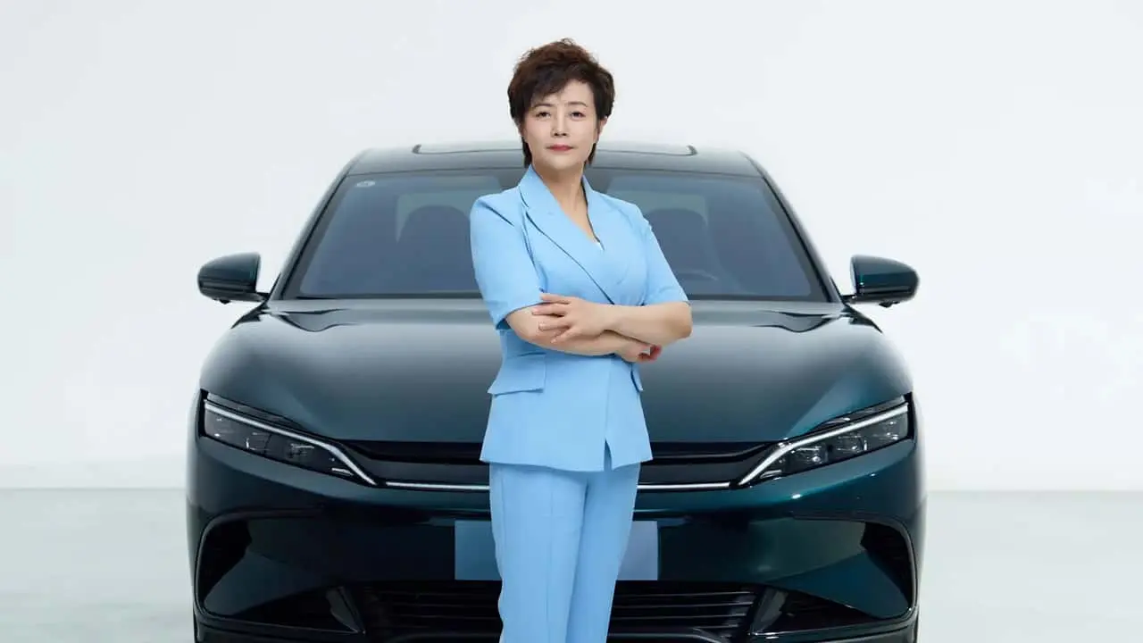nell'immagine si vede Stella Li, la numero due di BYD, che posa davanti ad un'auto del colosso di Schenzen