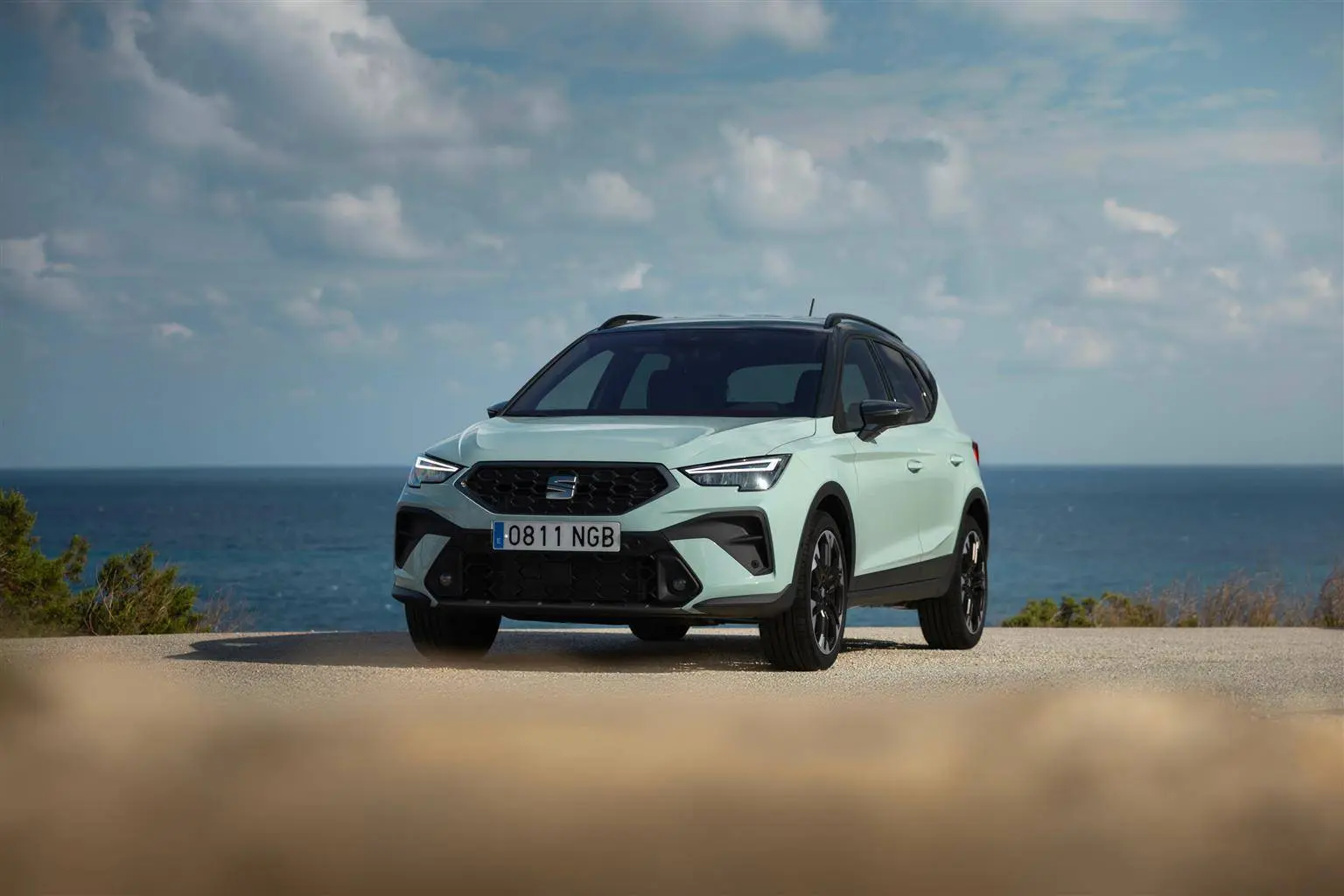 Nuova SEAT Arona di colore Azzurro parcheggiataa ripresa di fronte e con sfondo mare