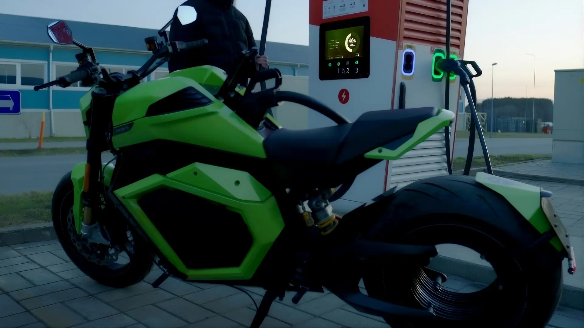 moto di colore verde modello verge ts pro. Moto elettrica con batteria donut lab che si sta ricaricando a una colonnina