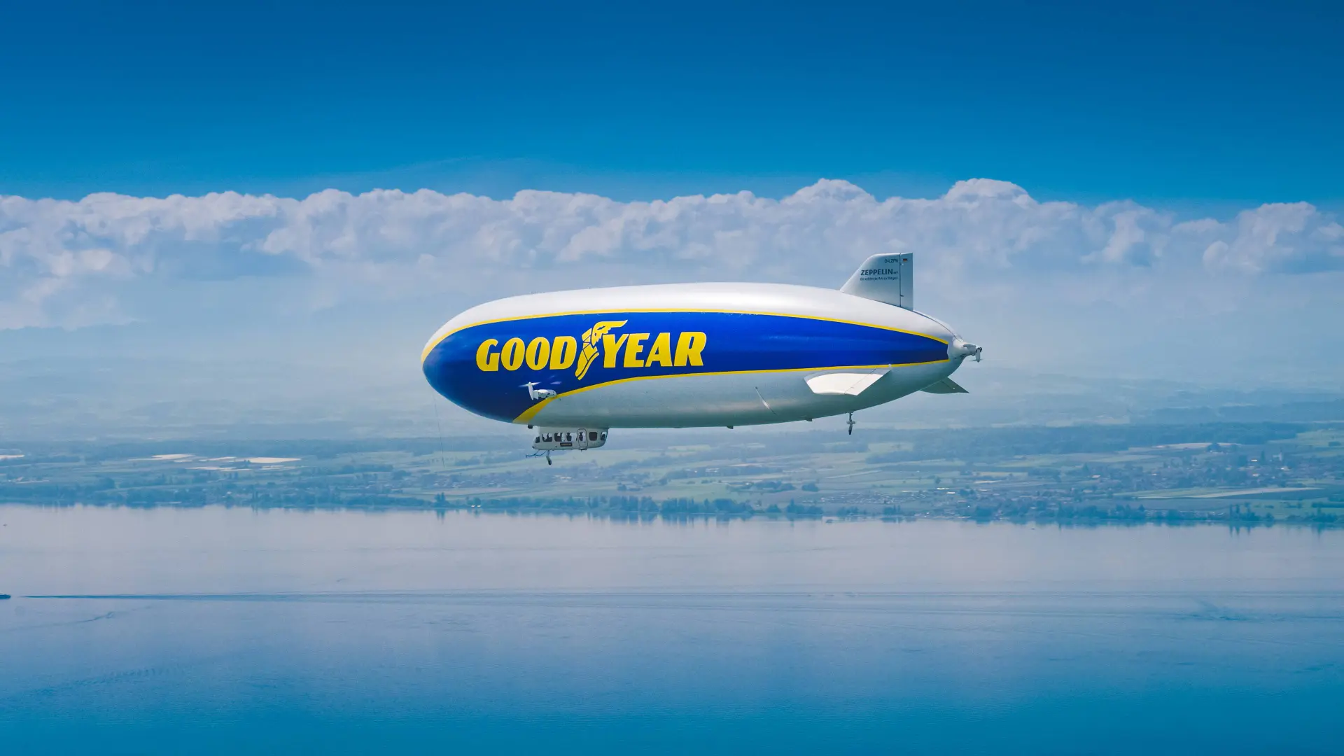 Dirigibile Goodyear che vola nei cieli sopra a un grande specchio d'acqua