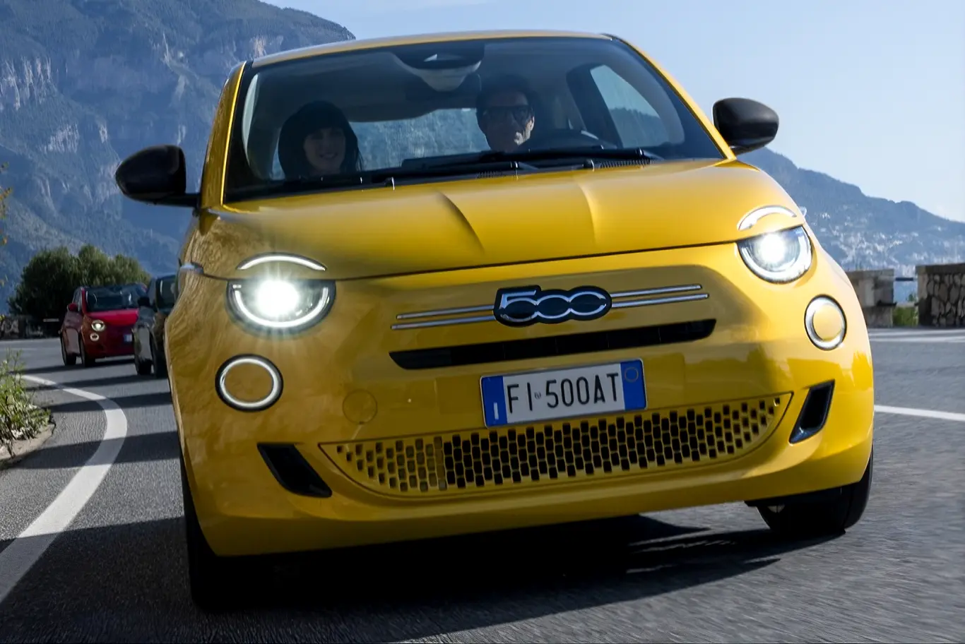 FIAT 500 ibrida di colore giallo che percorre strada ripresa di muso