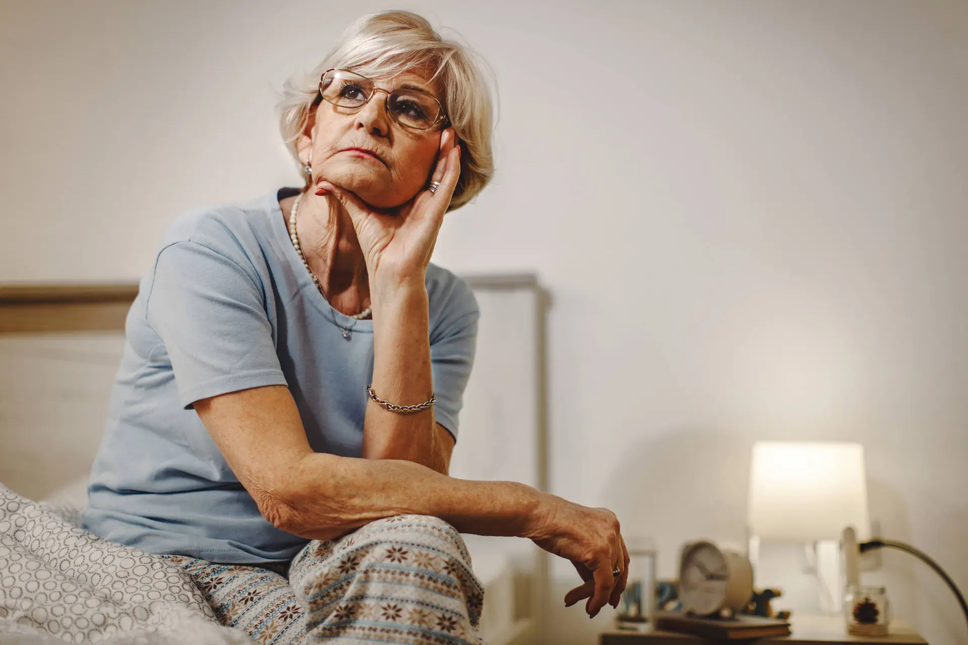 pensive mature woman thinking something while sitting bed