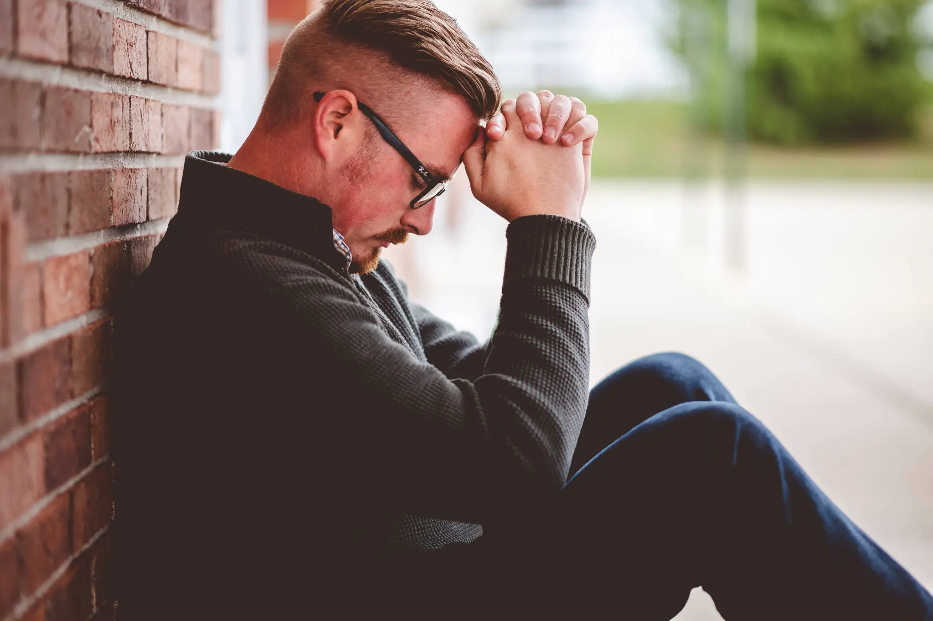 male sitting near wall while praying